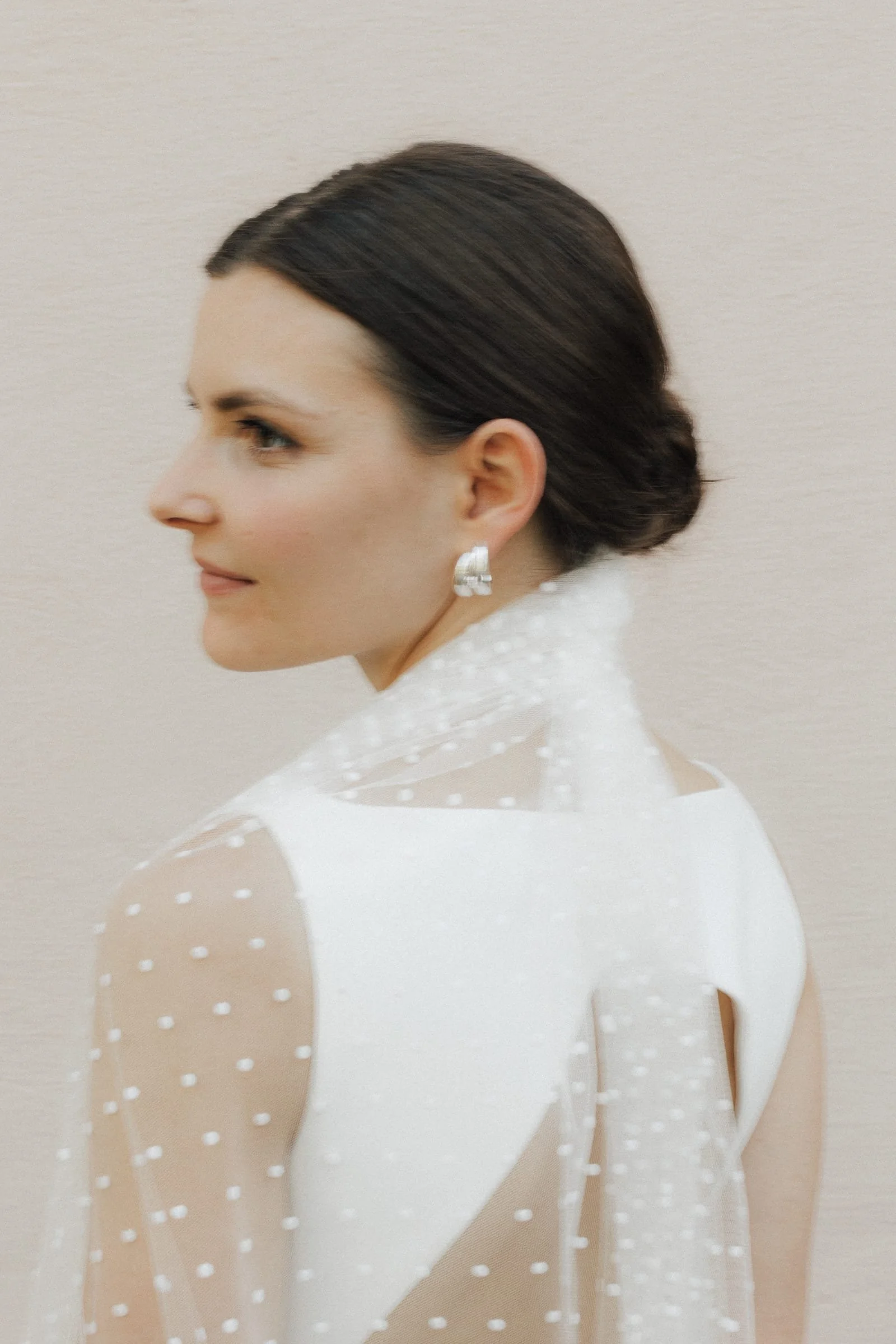 Stilvolles Porträt einer Braut mit tiefem Chignon und Statement-Brautschmuck