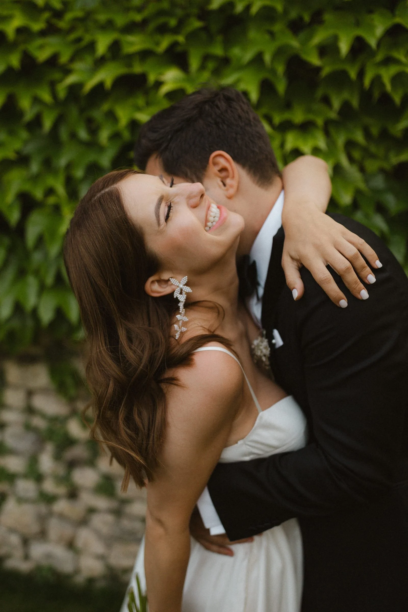 Modernes Brautpaar umarmt sich vor efeubewachsener Wand im Weingut Boudier Köller