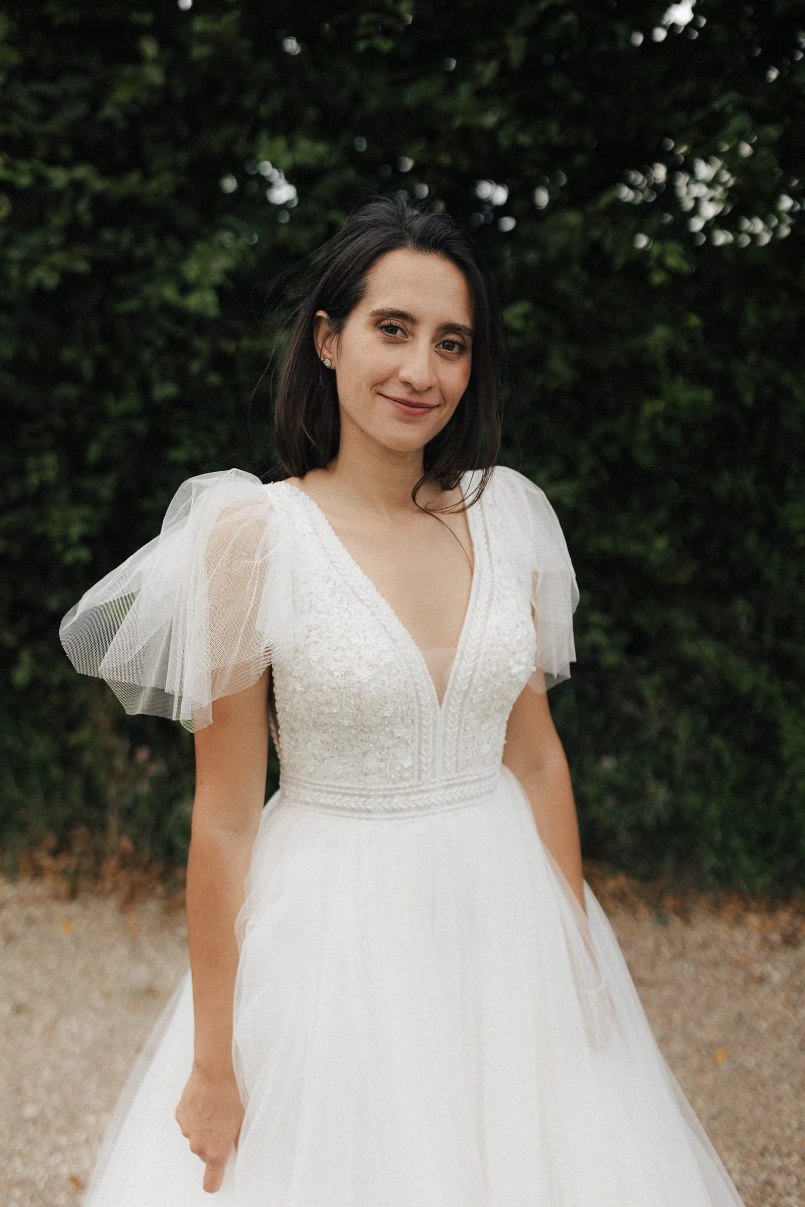 Elegante Braut mit neutralem Gesichtsausdruck vor einem grünen, bewaldeten Hintergrund in Schloss Walkershogen