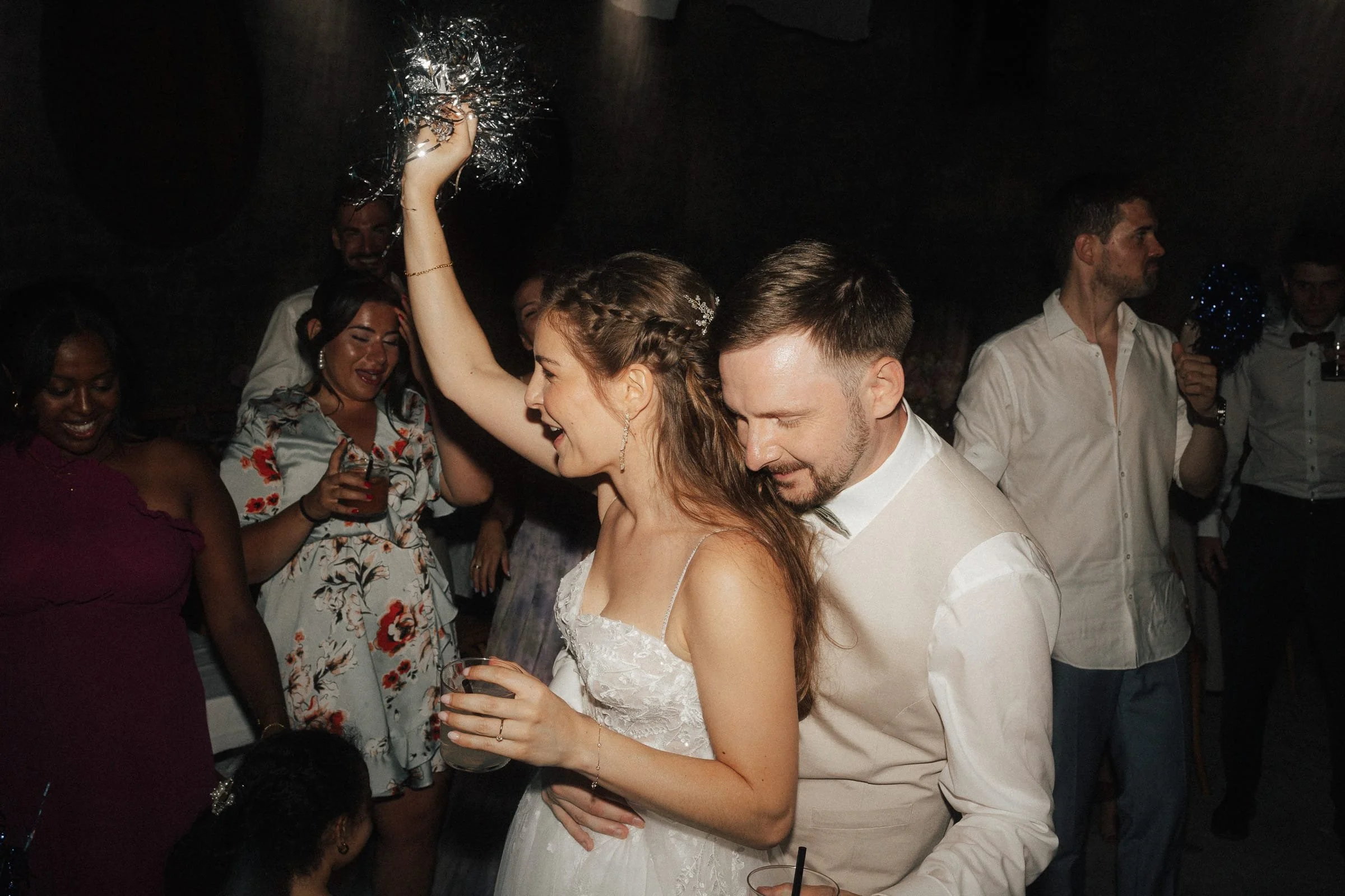 Paare und Gruppen feiern auf einer Hochzeitsparty, tanzen und haben Spaß, in einer dunklen Location mit stimmungsvoller Beleuchtung.