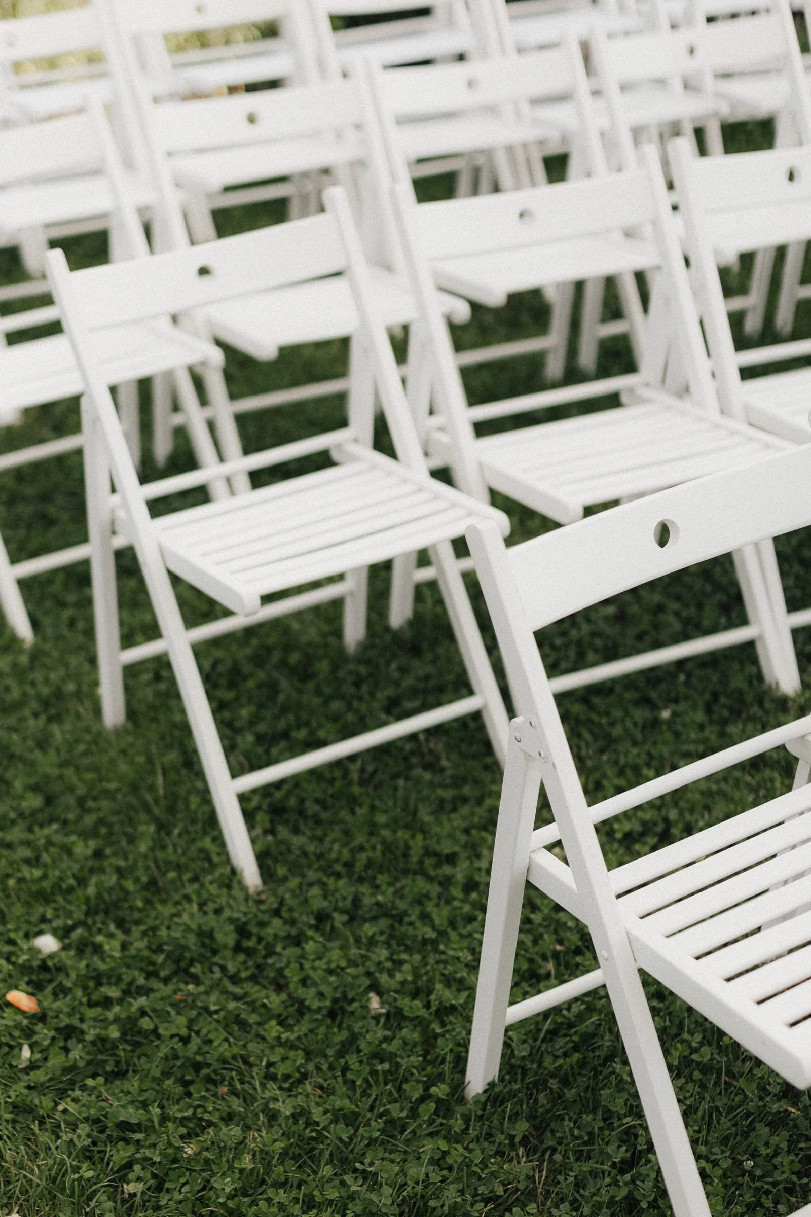Mehrere weiße Stühle auf grünem Gras für eine freie Trauung. 