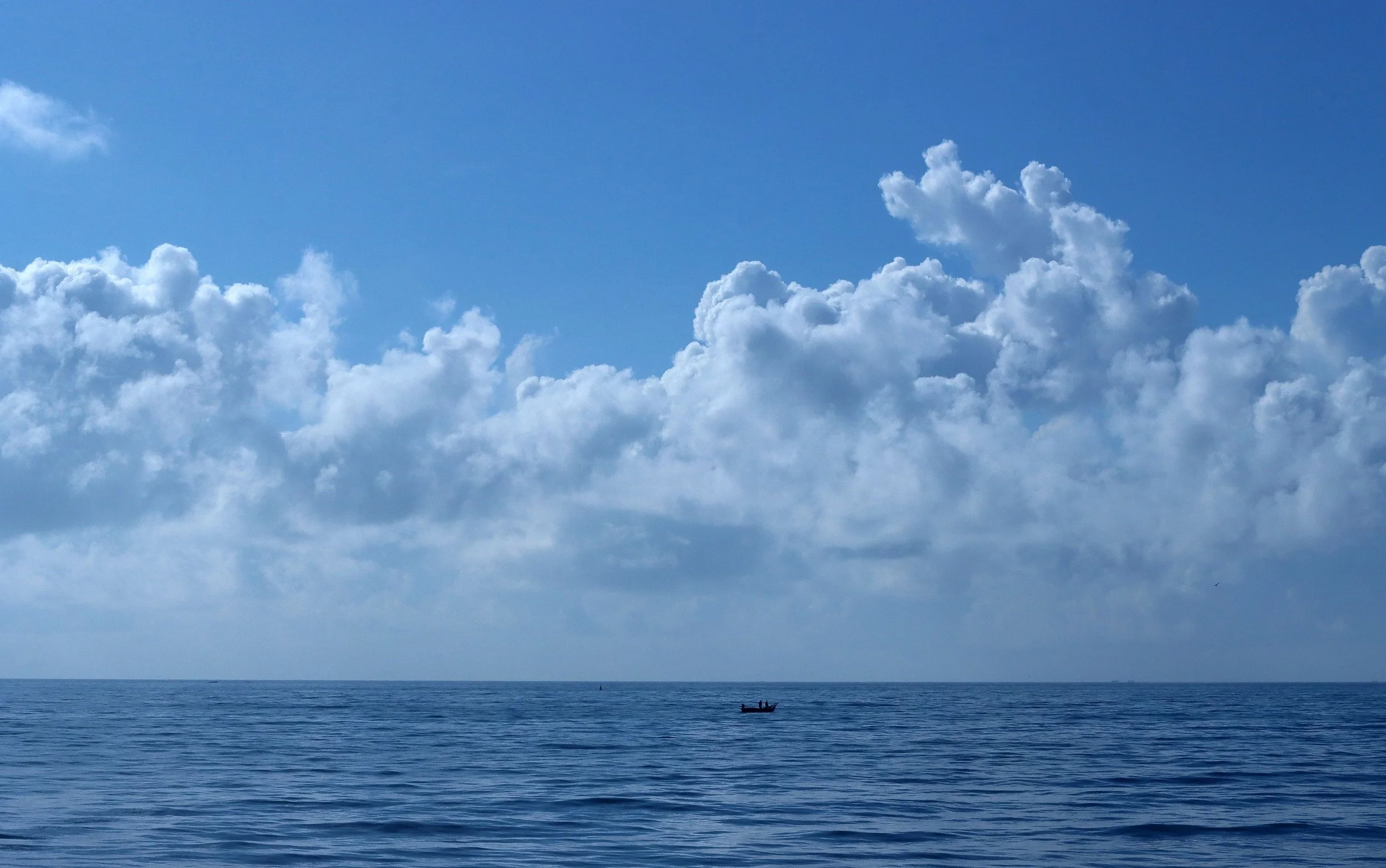 View out to a calm sea with blue sky and clouds. Generic image, no specified location. 