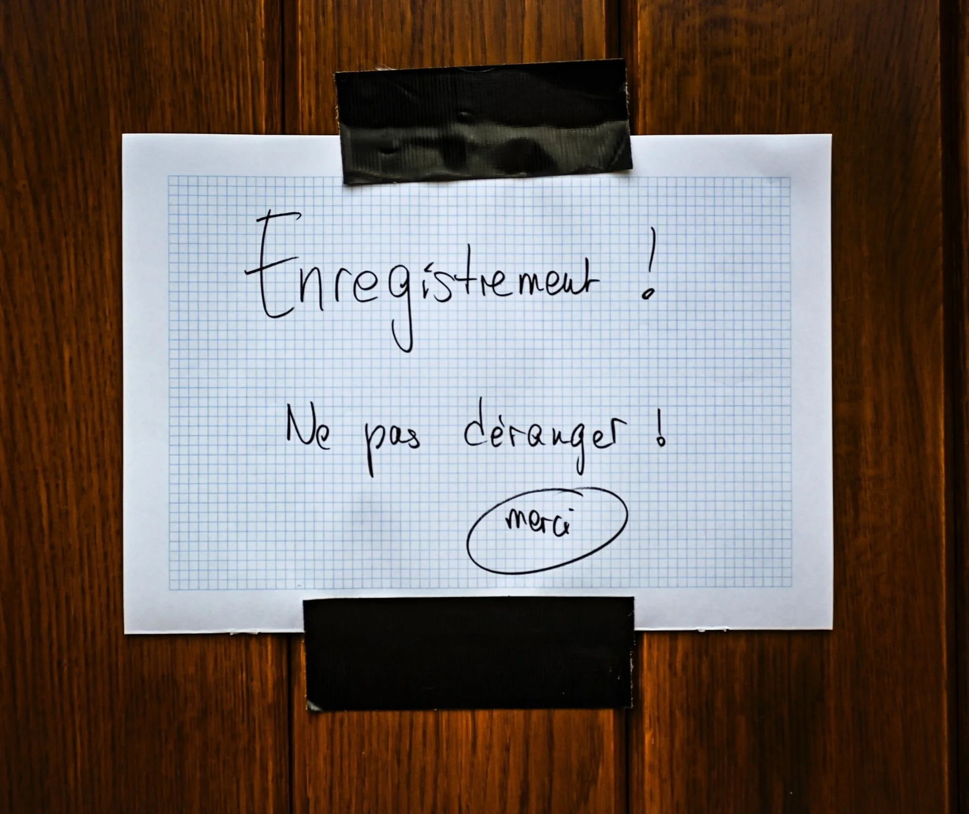 Panneau manuscrit « Enregistrement ! Ne pas déranger » scotché sur une porte