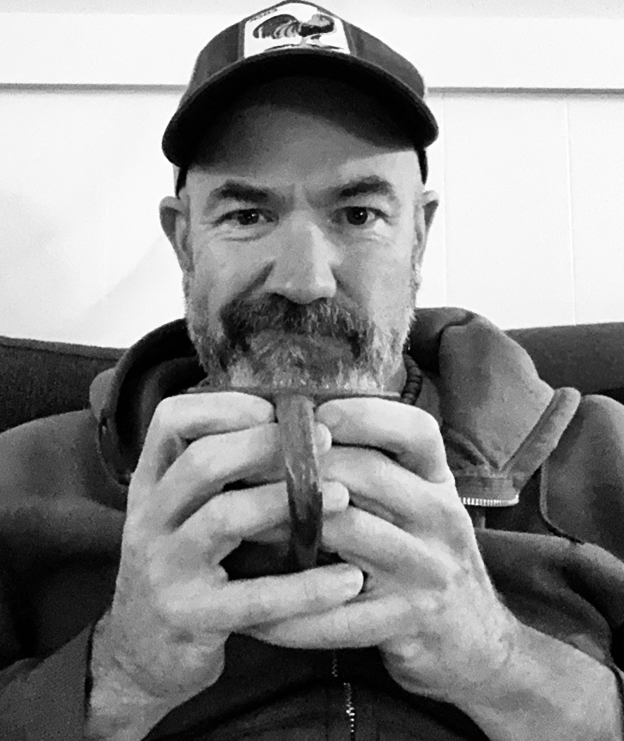 man in baseball cap sipping coffee