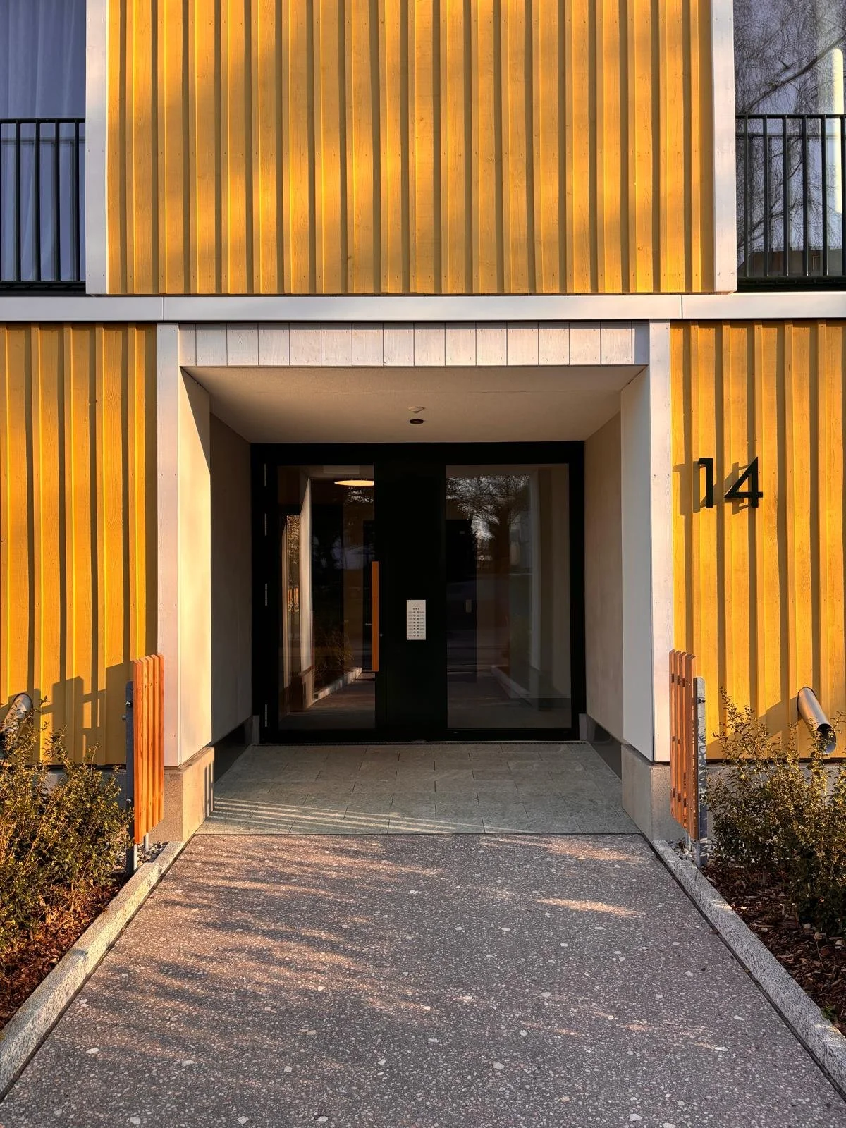 Contemporary architecture featuring yellow textured facade and natural stone entrance.