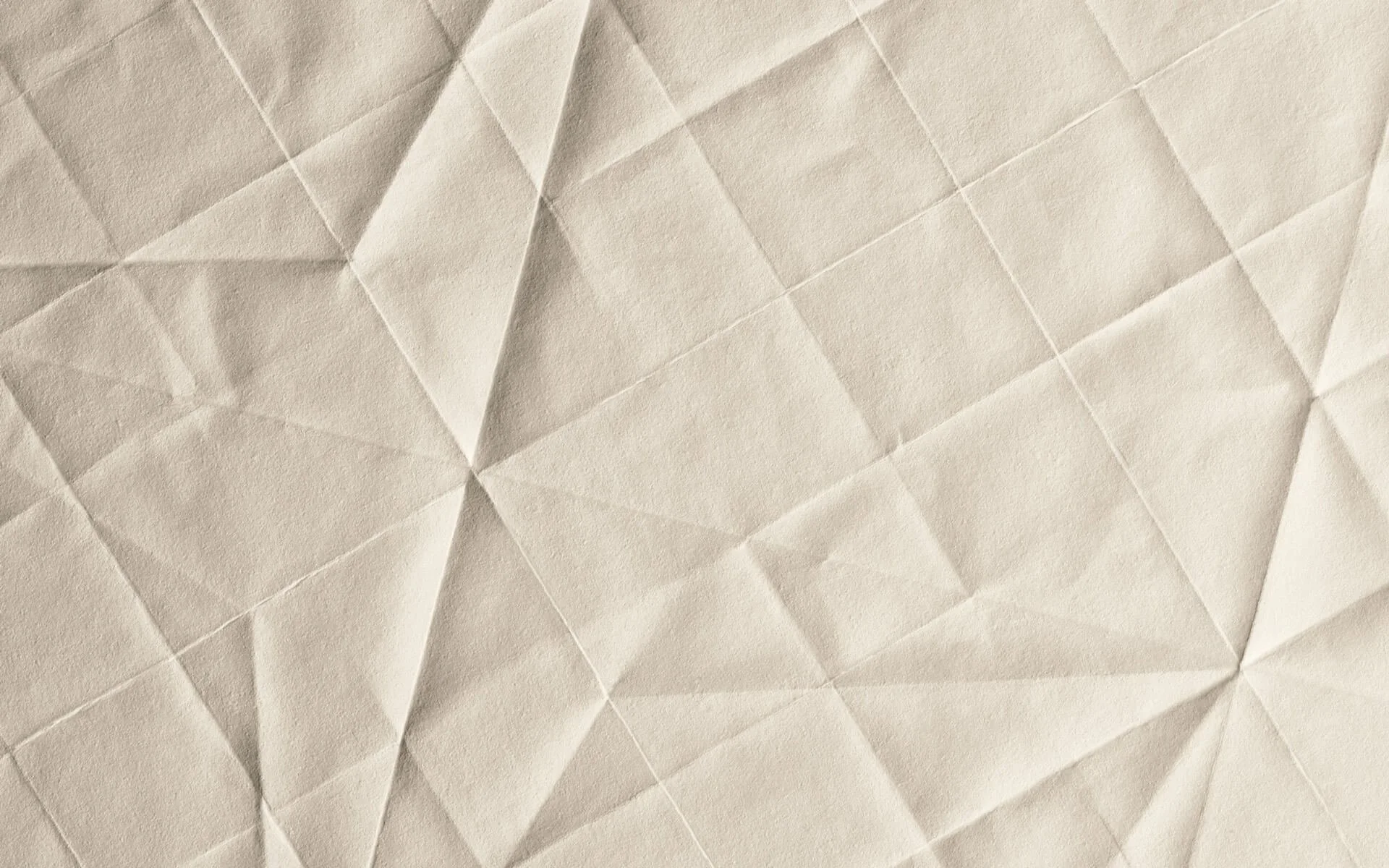 Nahaufnahme von zerknittertem cremefarbenem Papier mit geometrischen Linien und Mustern.
