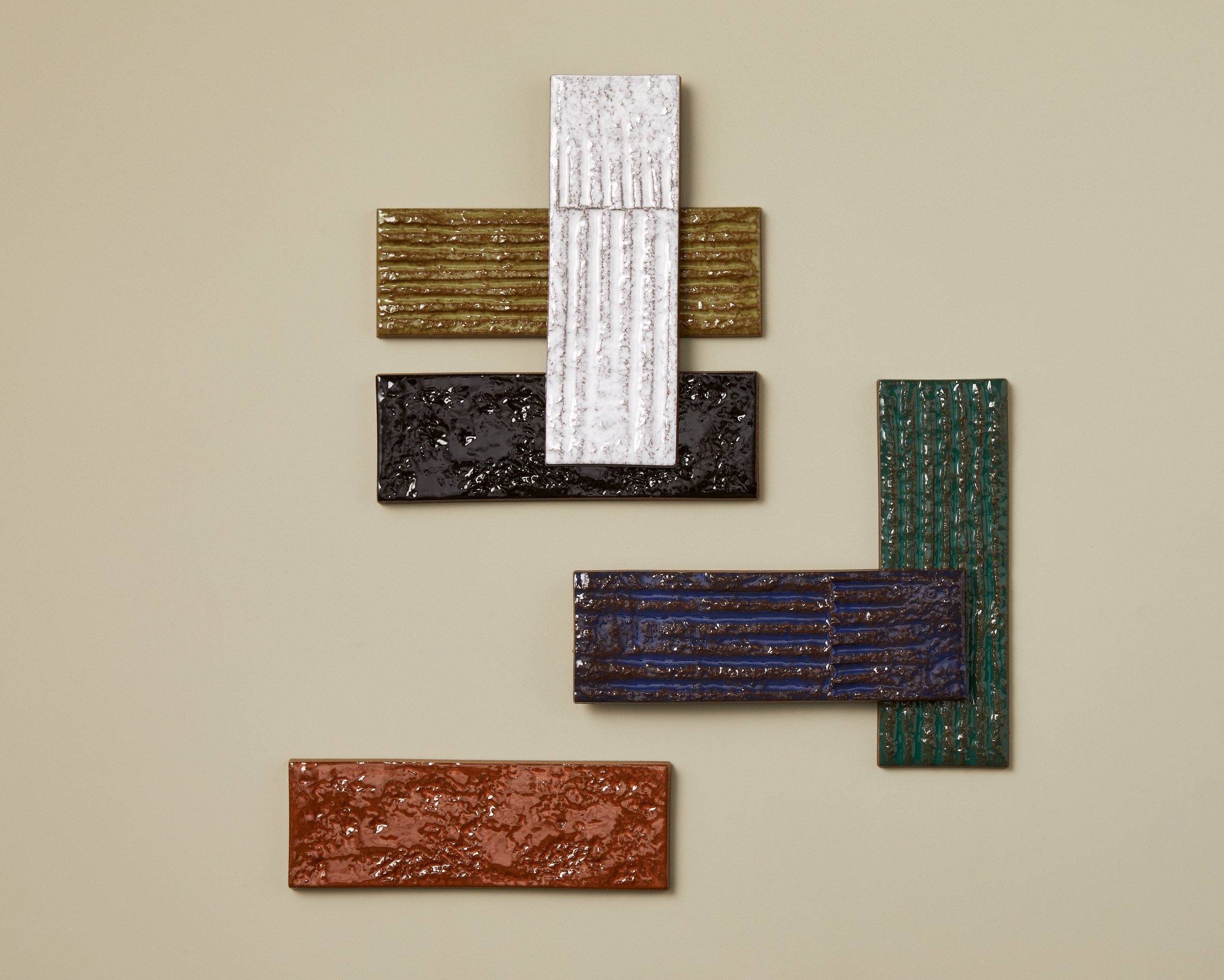 Abstrakte Wanddekoration aus bunten, texturierten rechteckigen Platten in verschiedenen Farben und Mustern.