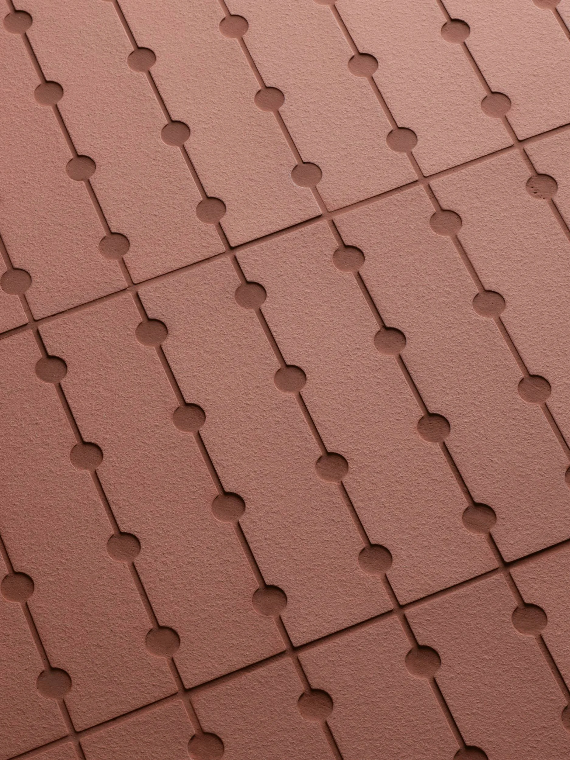 Nahaufnahme von runden, rötlich-braunen Fliesen mit erhabenen Linien zwischen ihnen.