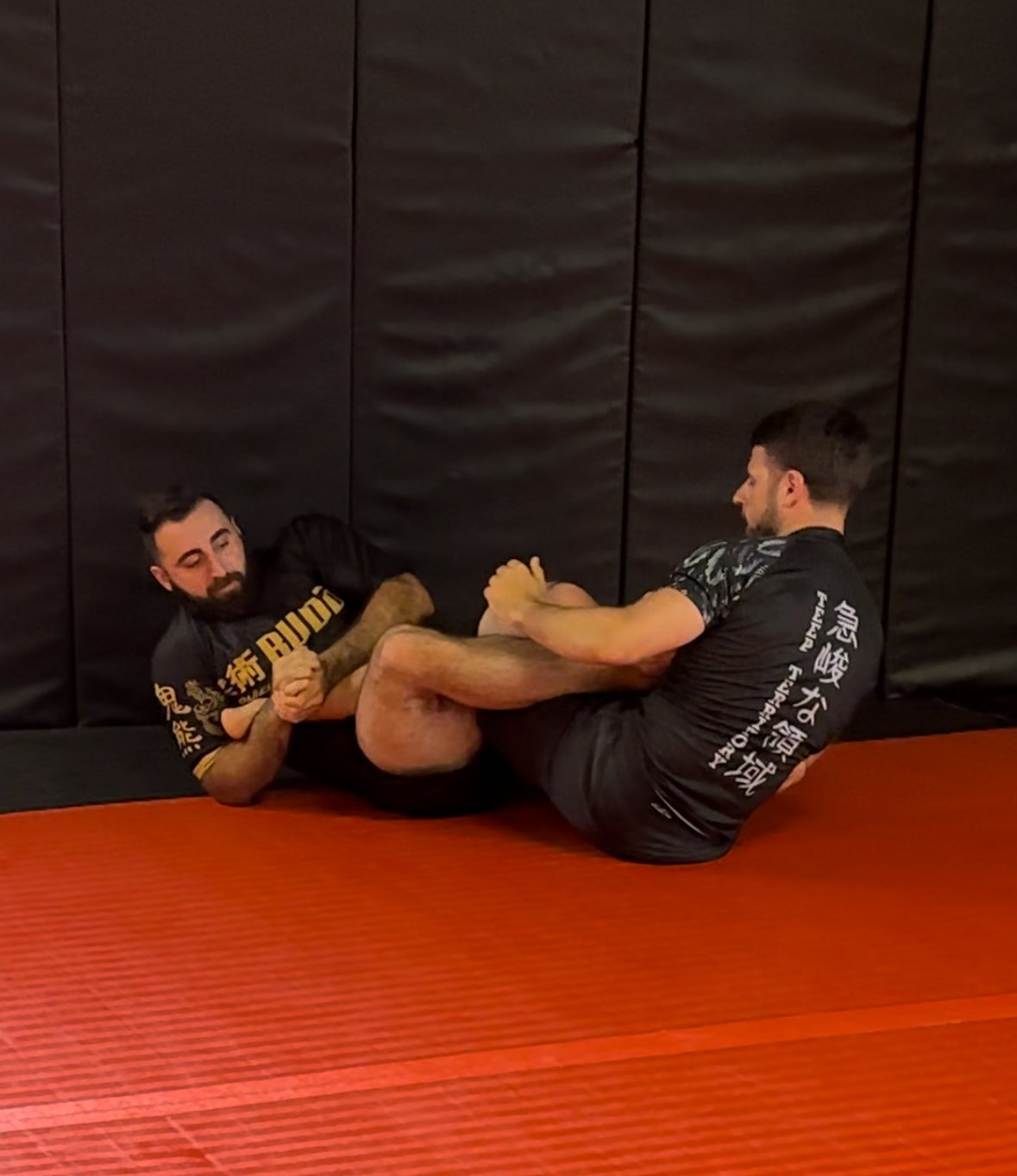 Two men practicing Brazilian Jiu-Jitsu one of which has a tightly locked heel hook - a submission that attacks the knee.