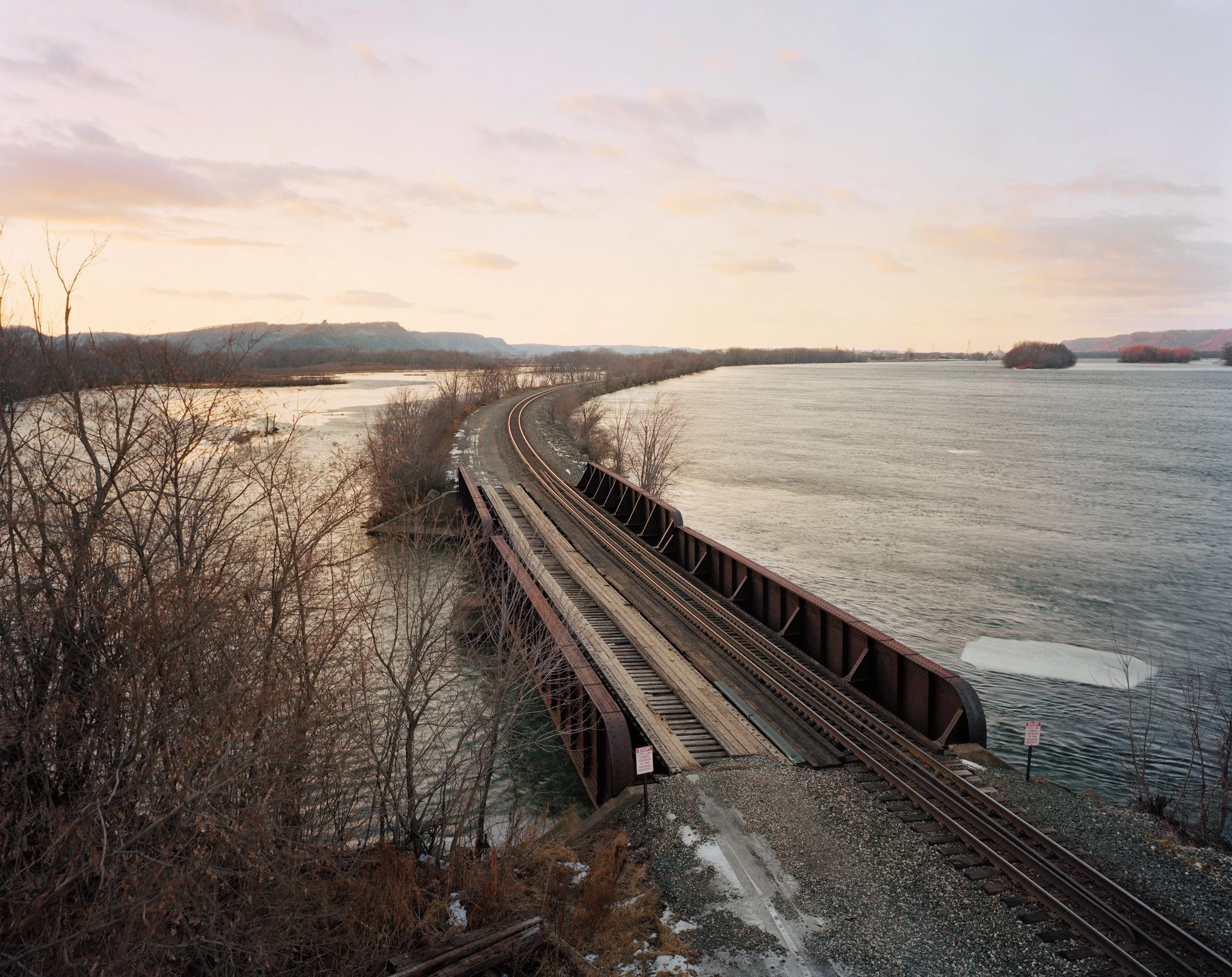 Leere Bahnstrecke, die über eine kurze Brücke über dem Wasser verläuft