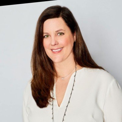 Headshot of a smiling woman with long dark hair, in a white top