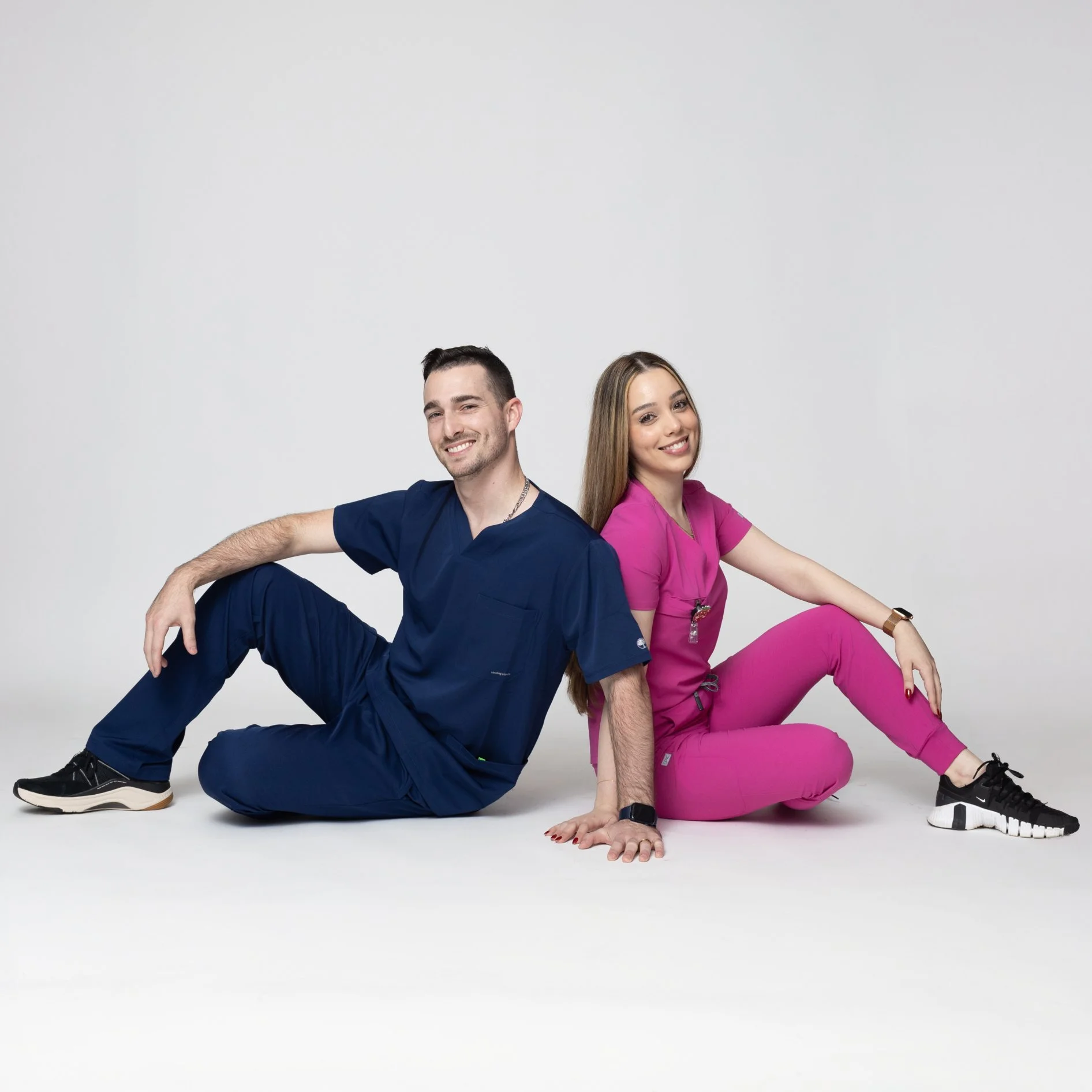 A man and woman pose wearing bayberry scrubs