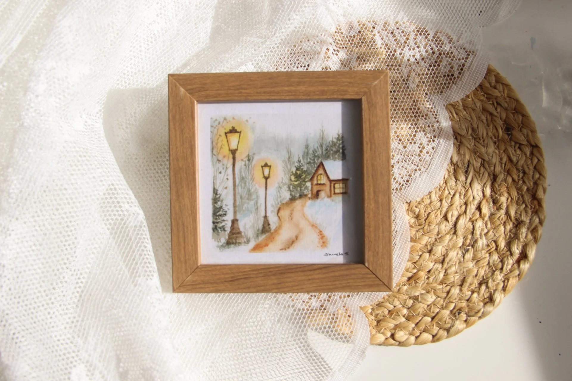 Light-up winter art print showing a snow-covered cottage under a glowing street lamp.