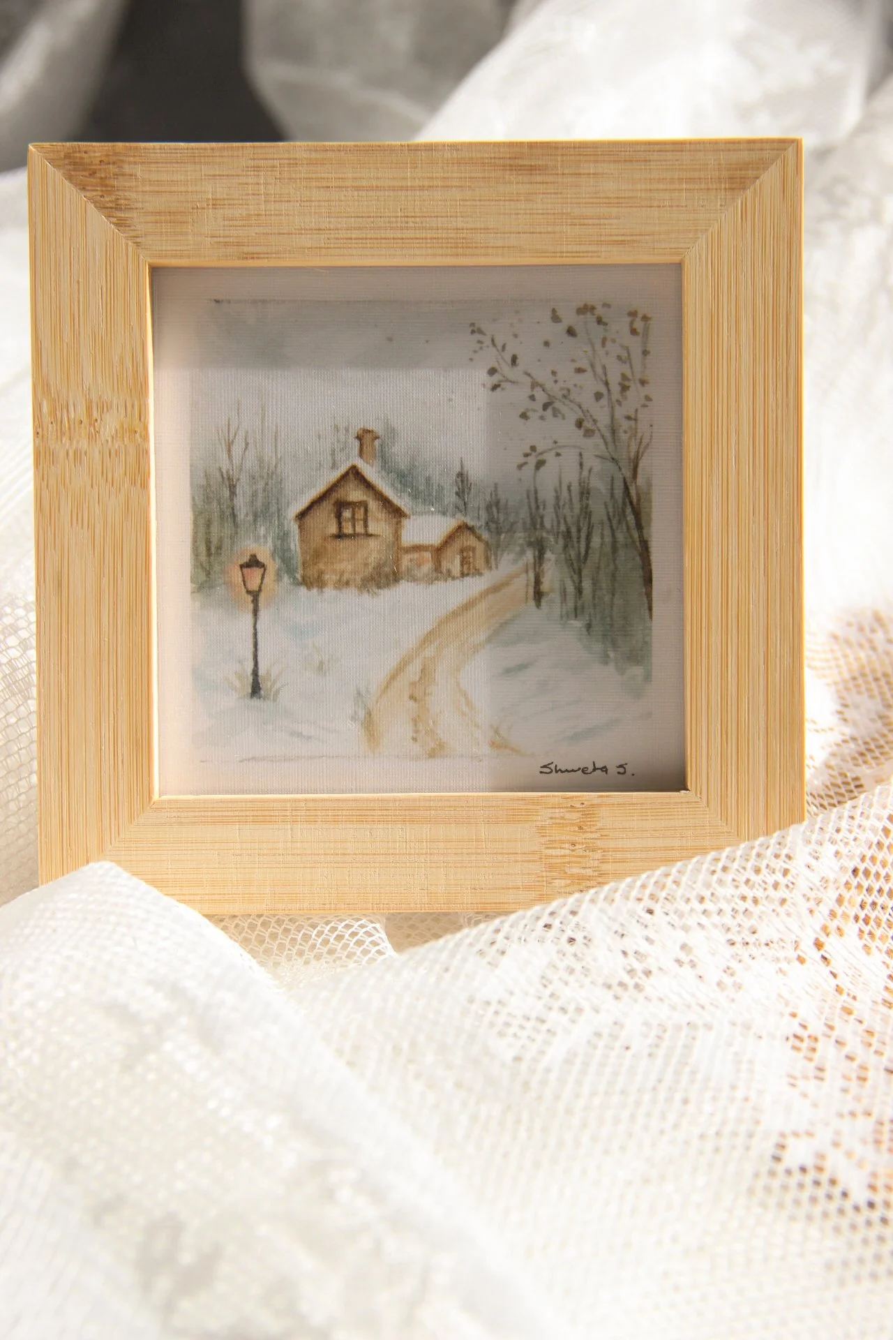 Light-up winter art print showing a snow-covered cottage under a glowing street lamp.