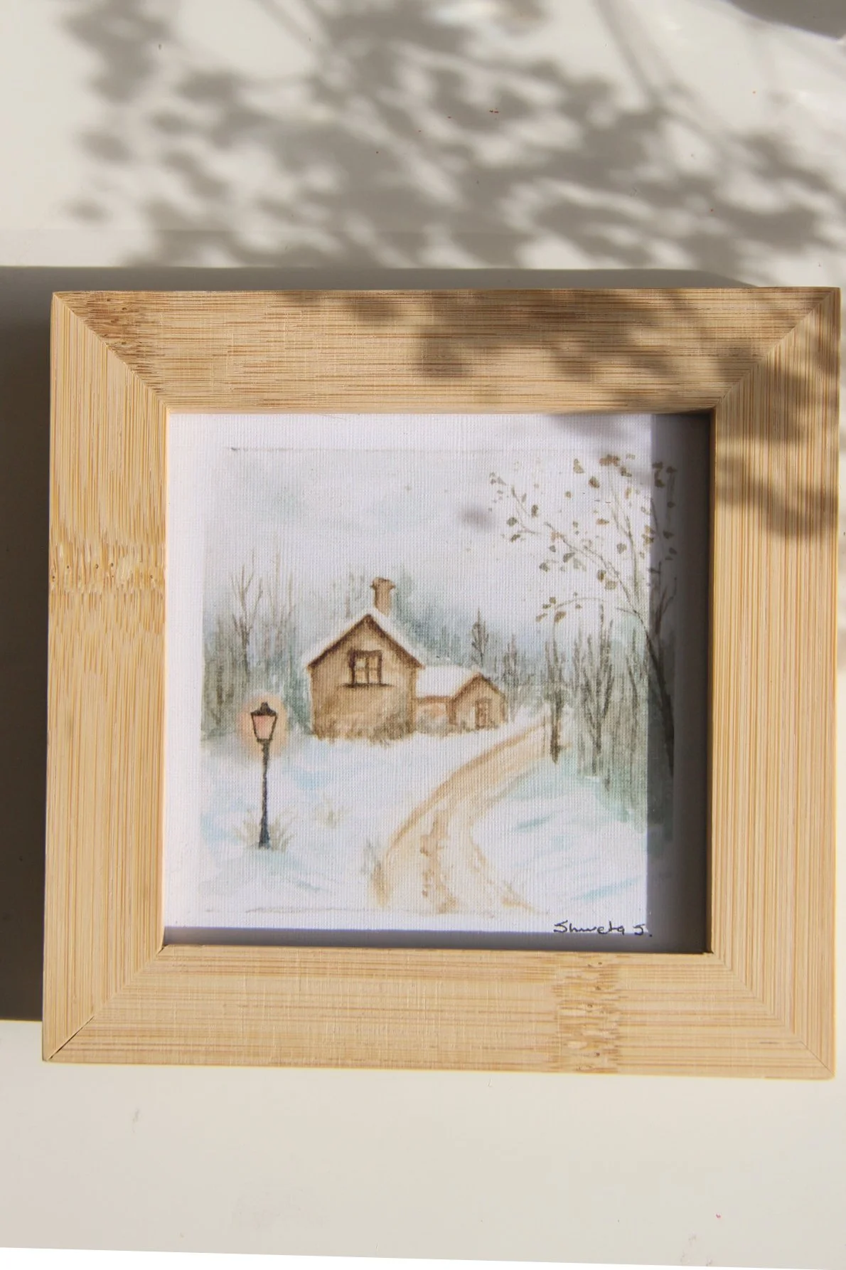 Light-up winter art print showing a snow-covered cottage under a glowing street lamp.