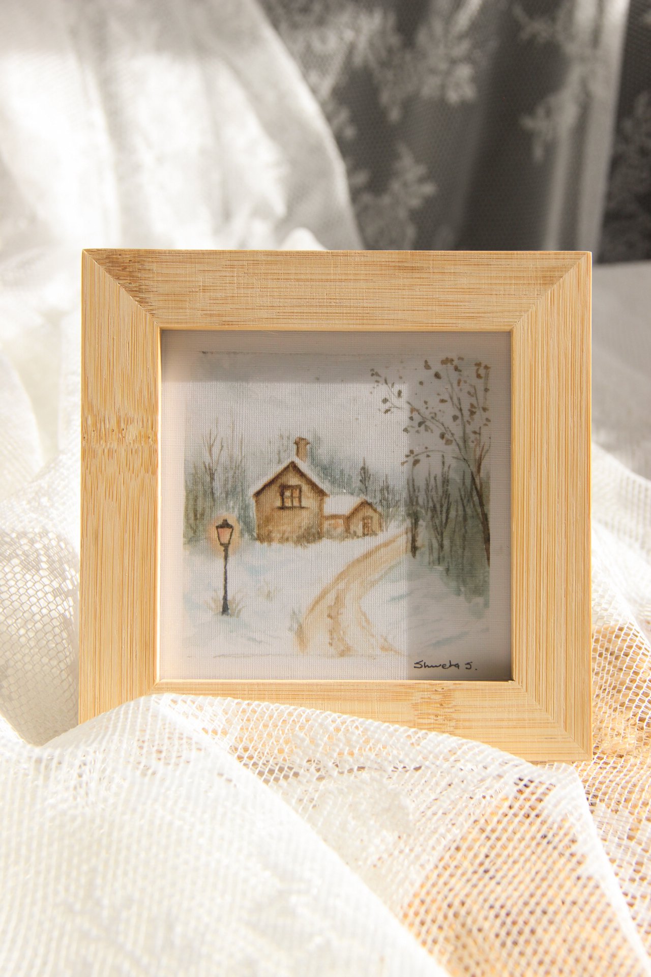Light-up winter art print showing a snow-covered cottage under a glowing street lamp.