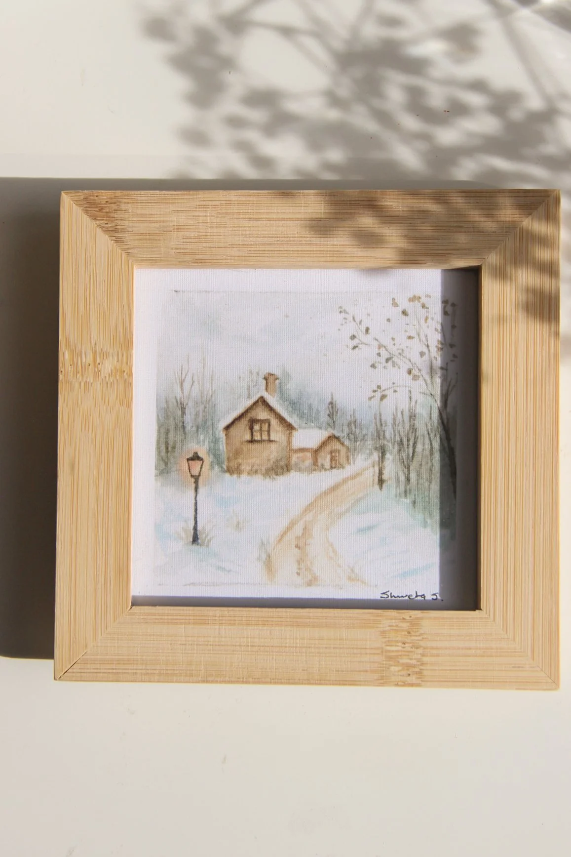 Light-up winter art print showing a snow-covered cottage under a glowing street lamp.