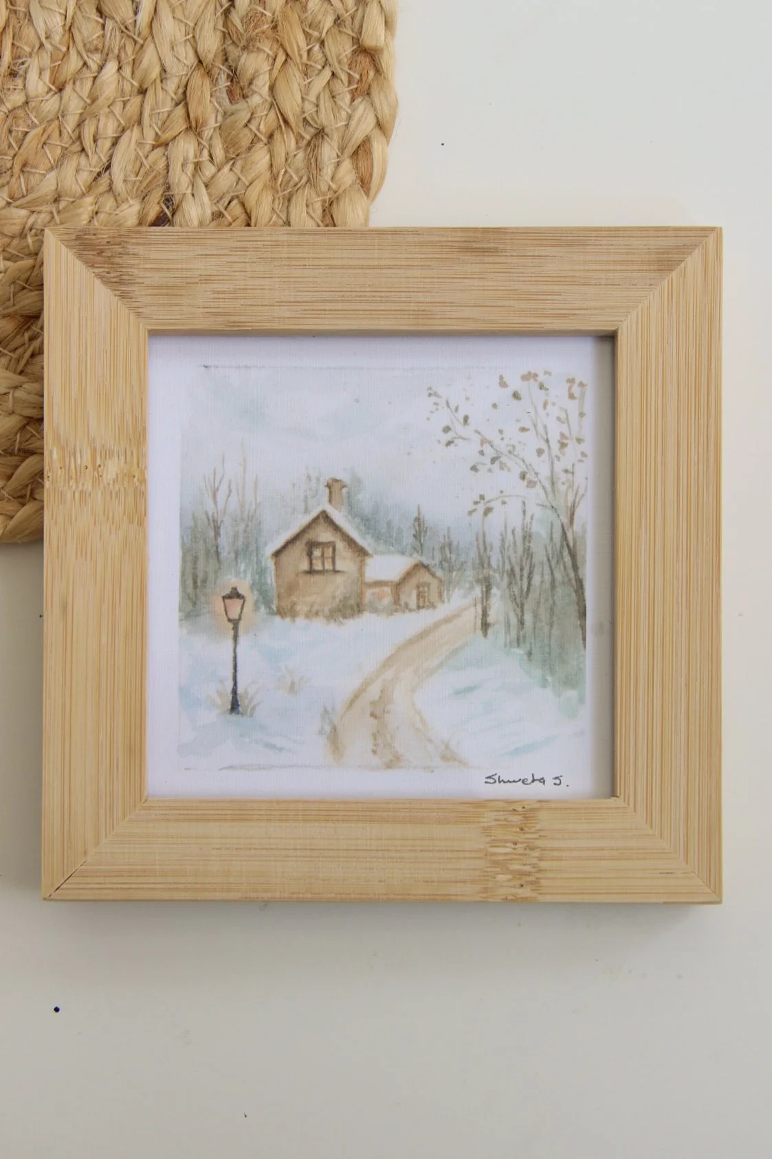 Light-up winter art print showing a snow-covered cottage under a glowing street lamp.