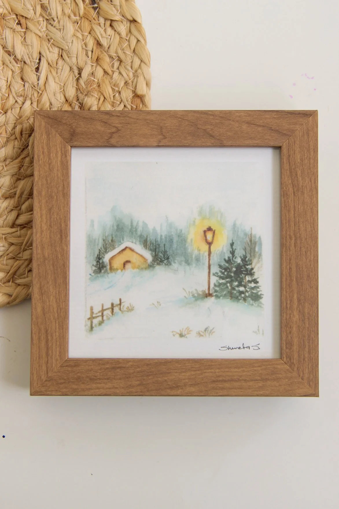 Light-up winter art print showing a snow-covered cottage under a glowing street lamp.
