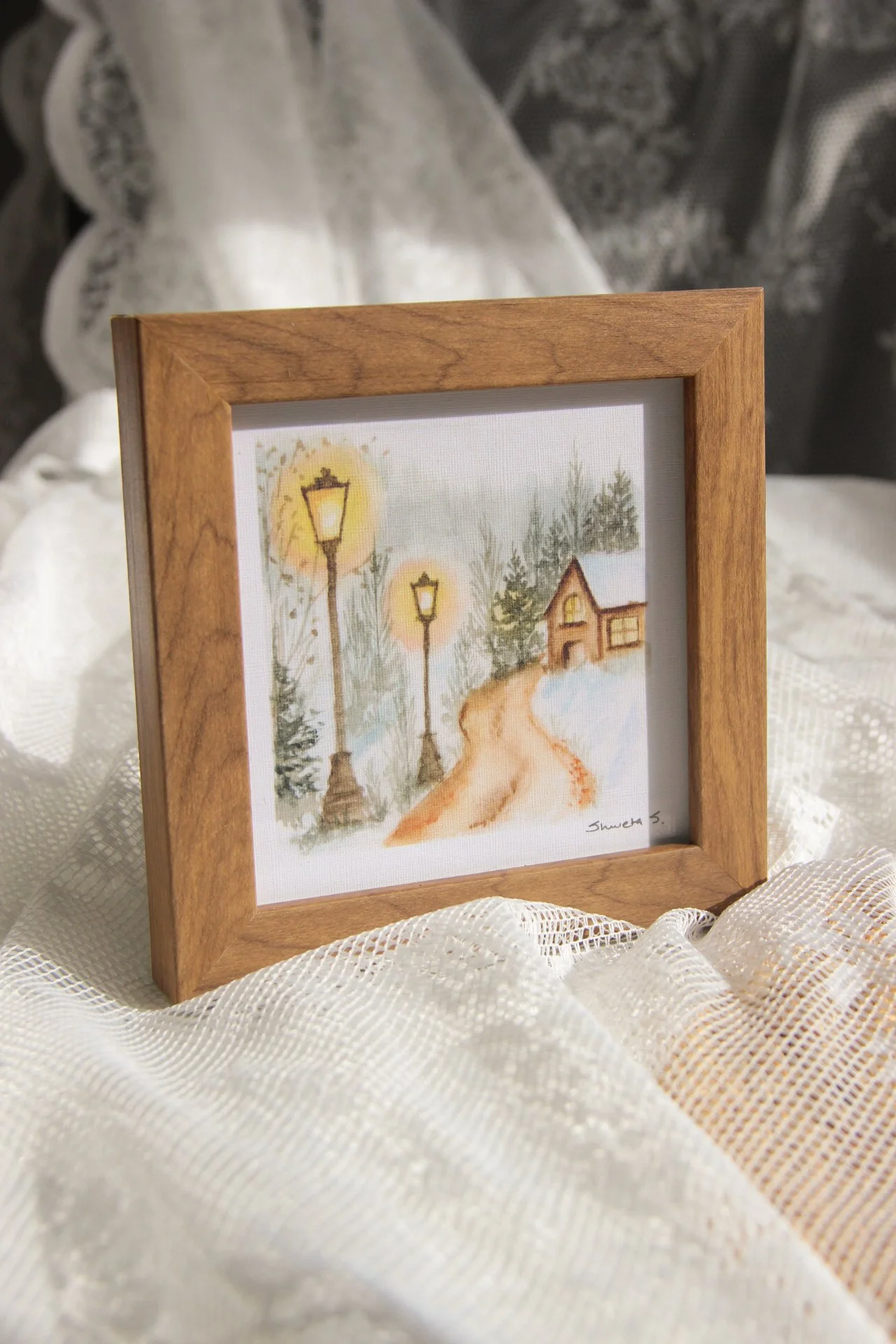 Light-up winter art print showing a snow-covered cottage under a glowing street lamp.