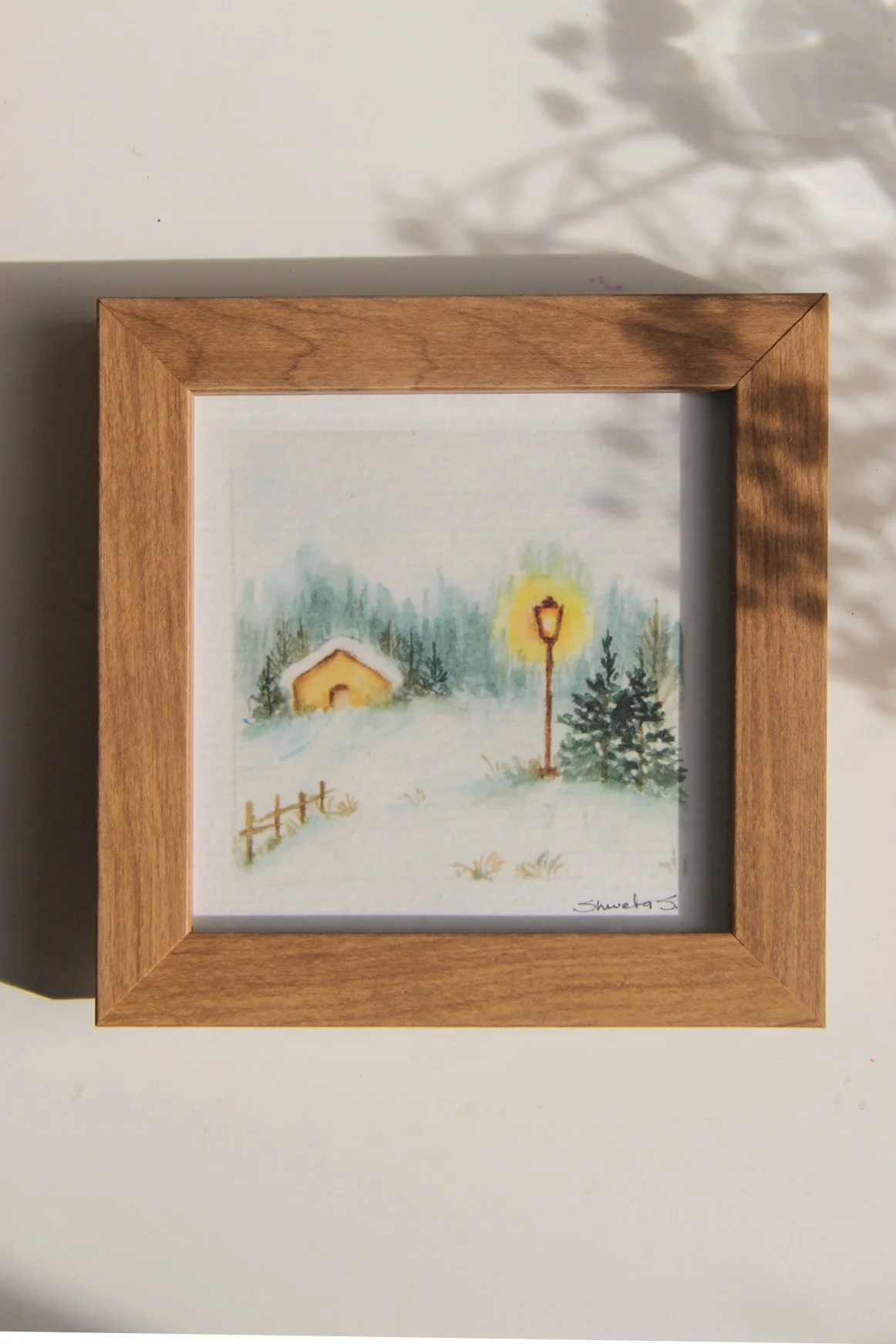 Light-up winter art print showing a snow-covered cottage under a glowing street lamp.