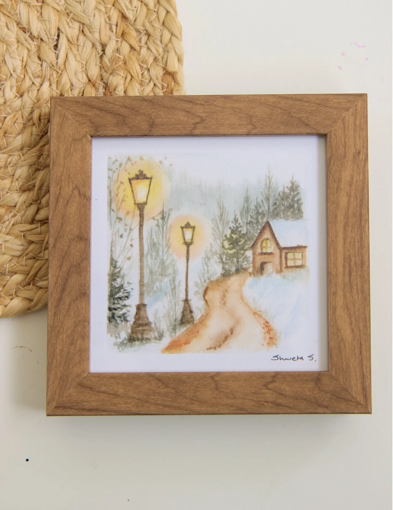 Light-up winter art print showing a snow-covered cottage under a glowing street lamp.