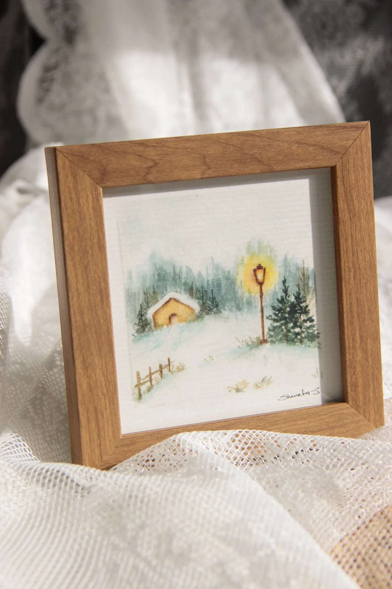 Light-up winter art print showing a snow-covered cottage under a glowing street lamp.
