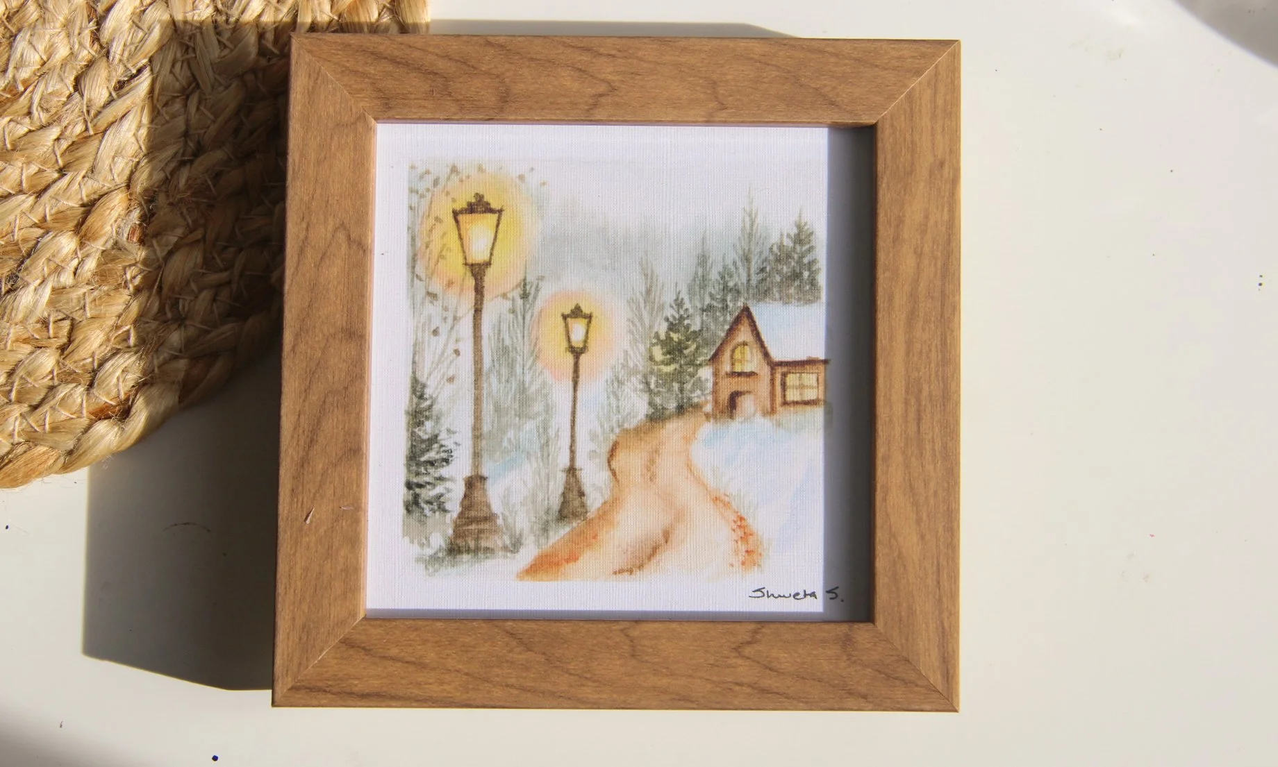 Light-up winter art print showing a snow-covered cottage under a glowing street lamp.