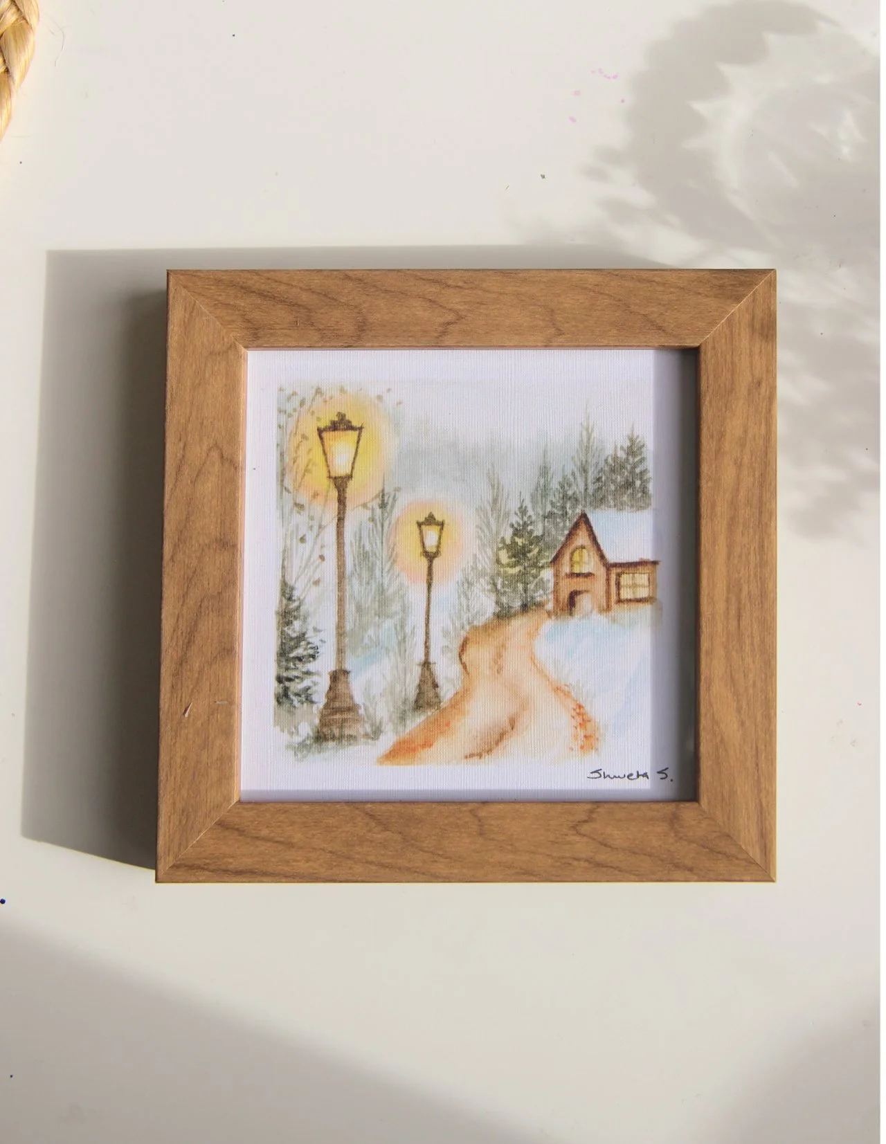 Light-up winter art print showing a snow-covered cottage under a glowing street lamp.