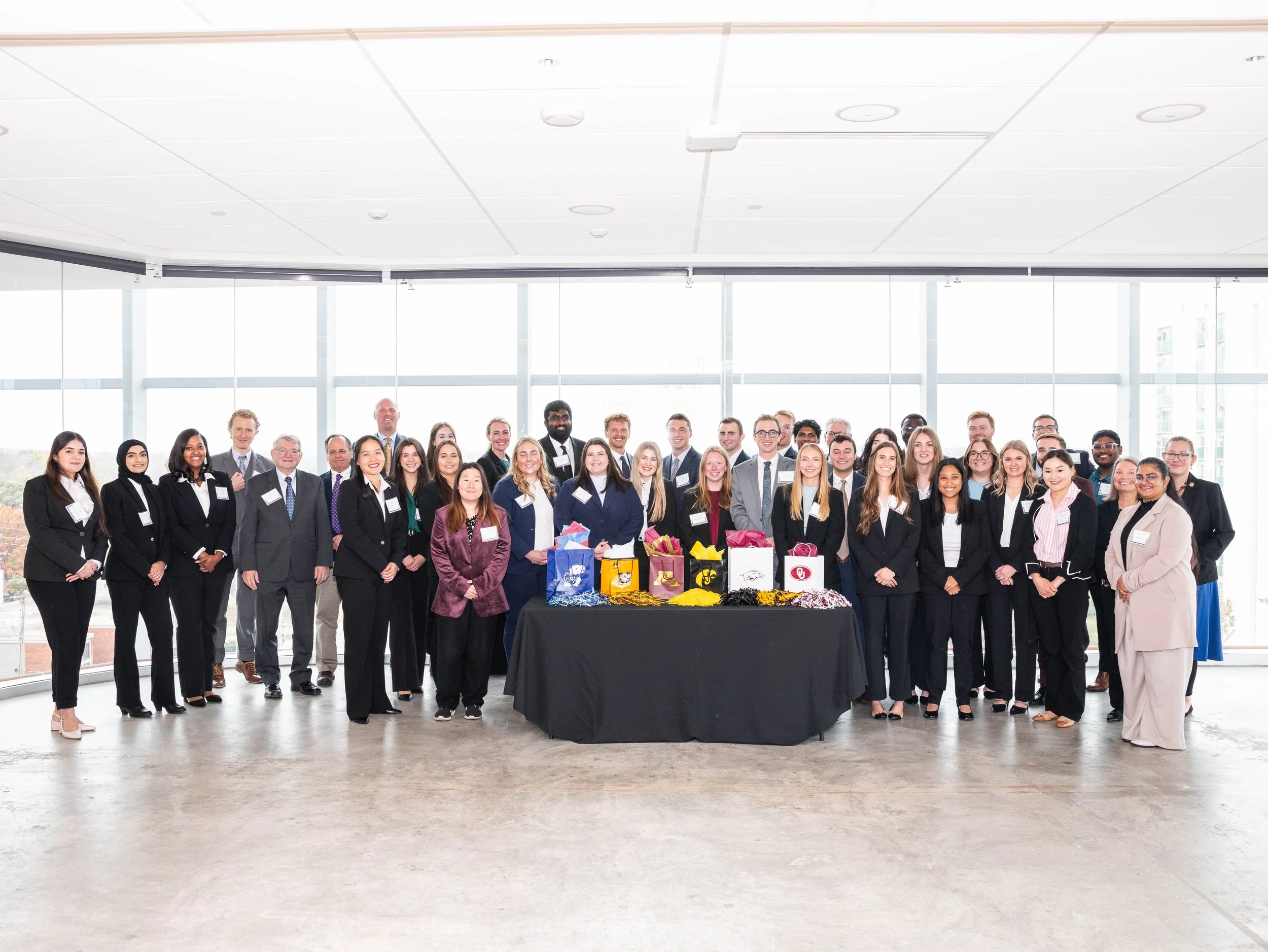 Group of people gathered outdoors around a sign that says "Eskridge 1900" during autumn with colorful fall trees in the background.