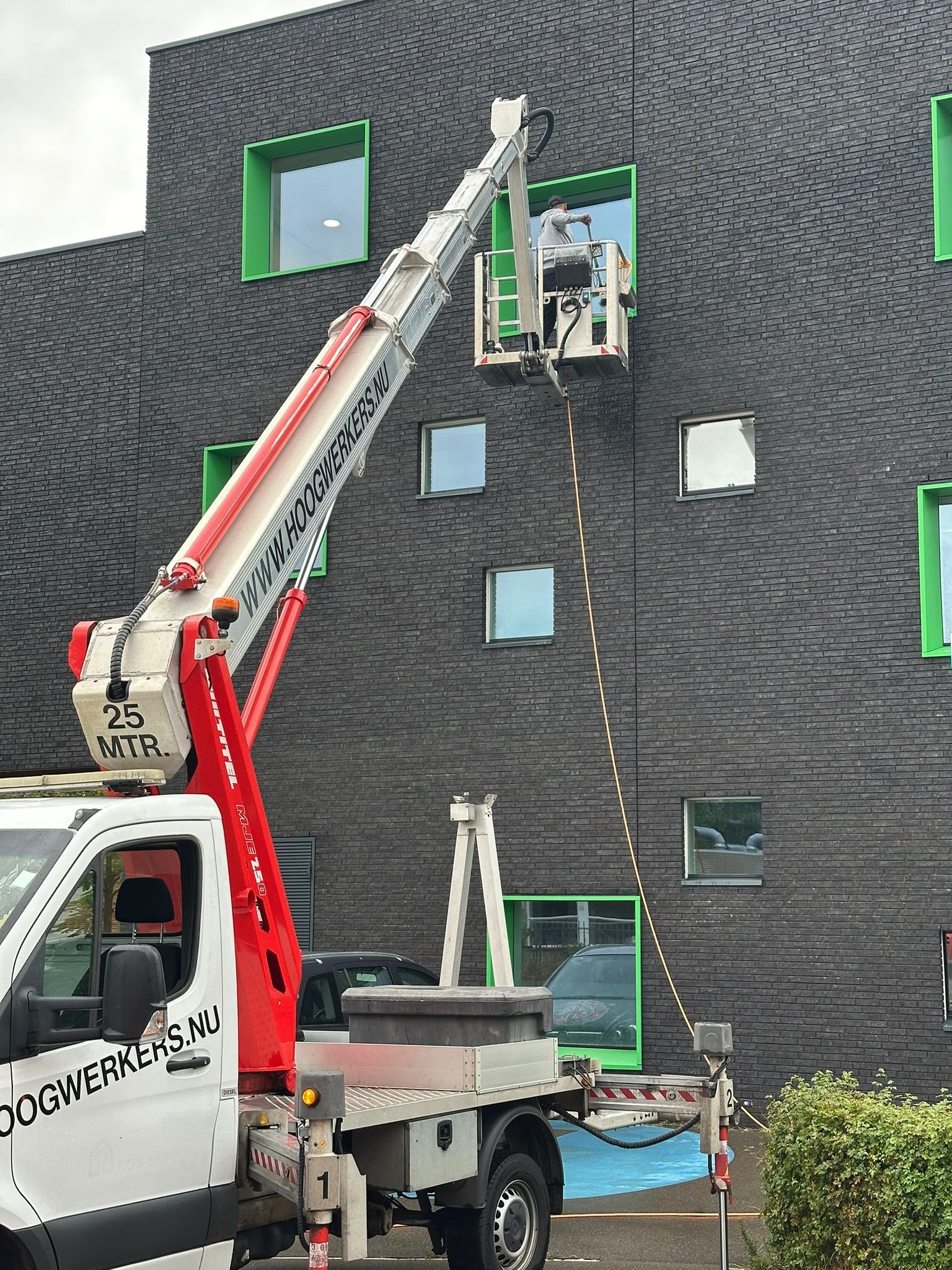 Glazenwasser reinigt ramen op hoogte met een hoogwerker.