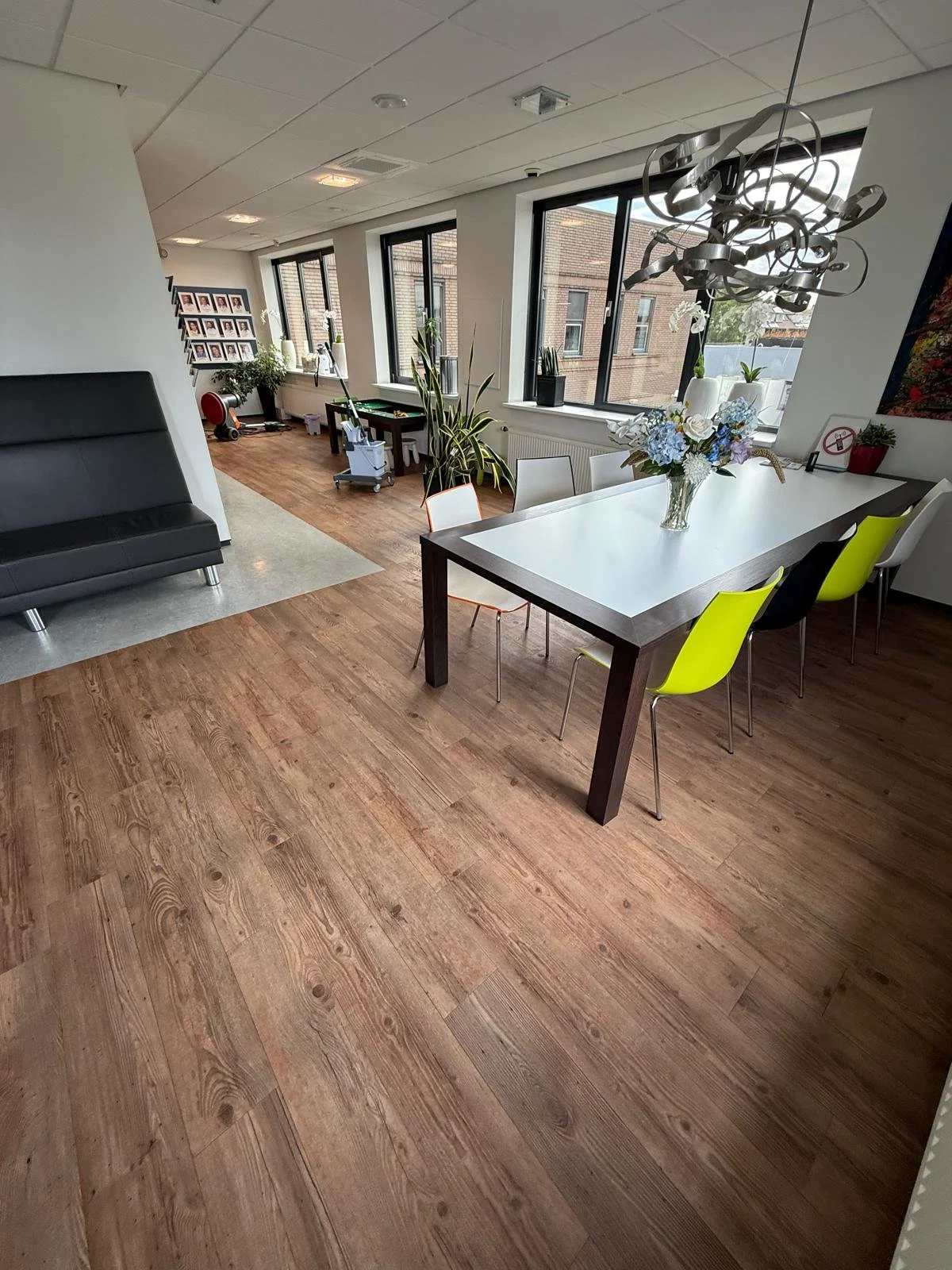 Schone bedrijfsruimte met houten vloer, tafels en stoelen na professionele schoonmaak.