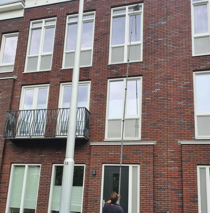 Glasbewassing van ramen in een appartementencomplex met een telescoopsysteem.