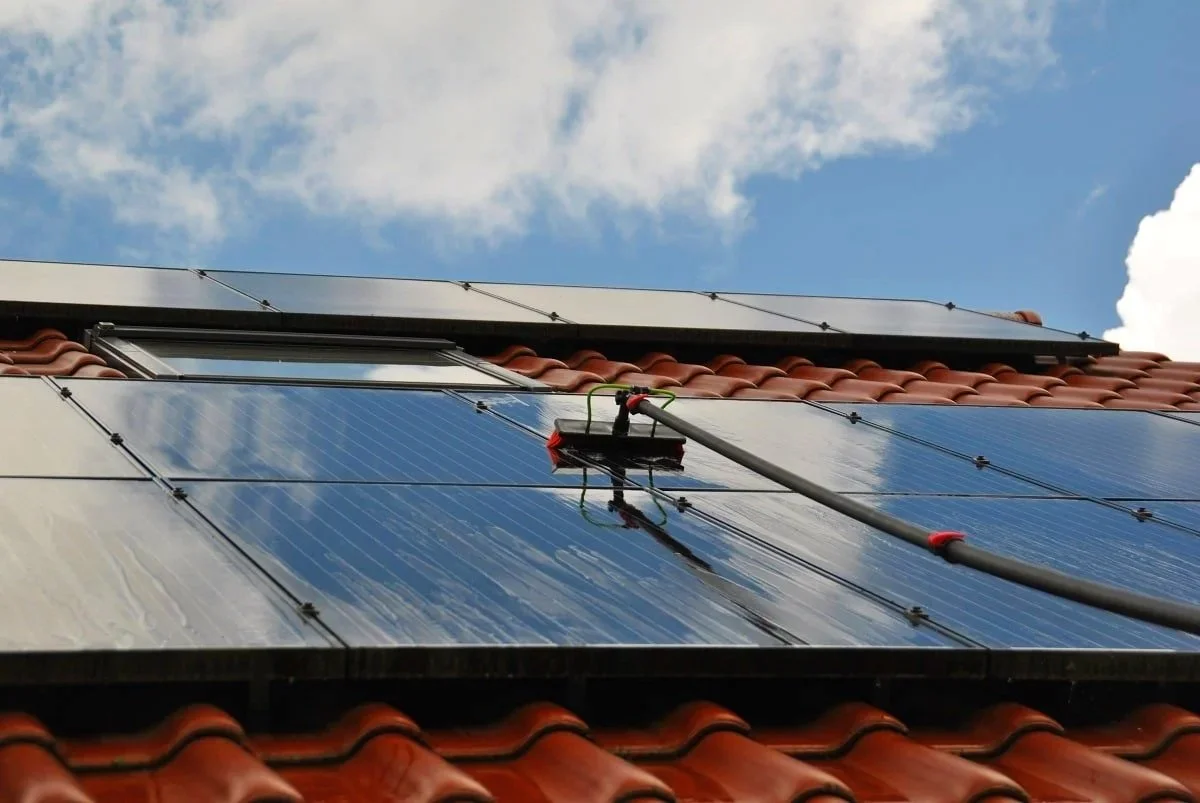 Zonnepanelen reinigen met een zachte borstel op een telescopische steel.