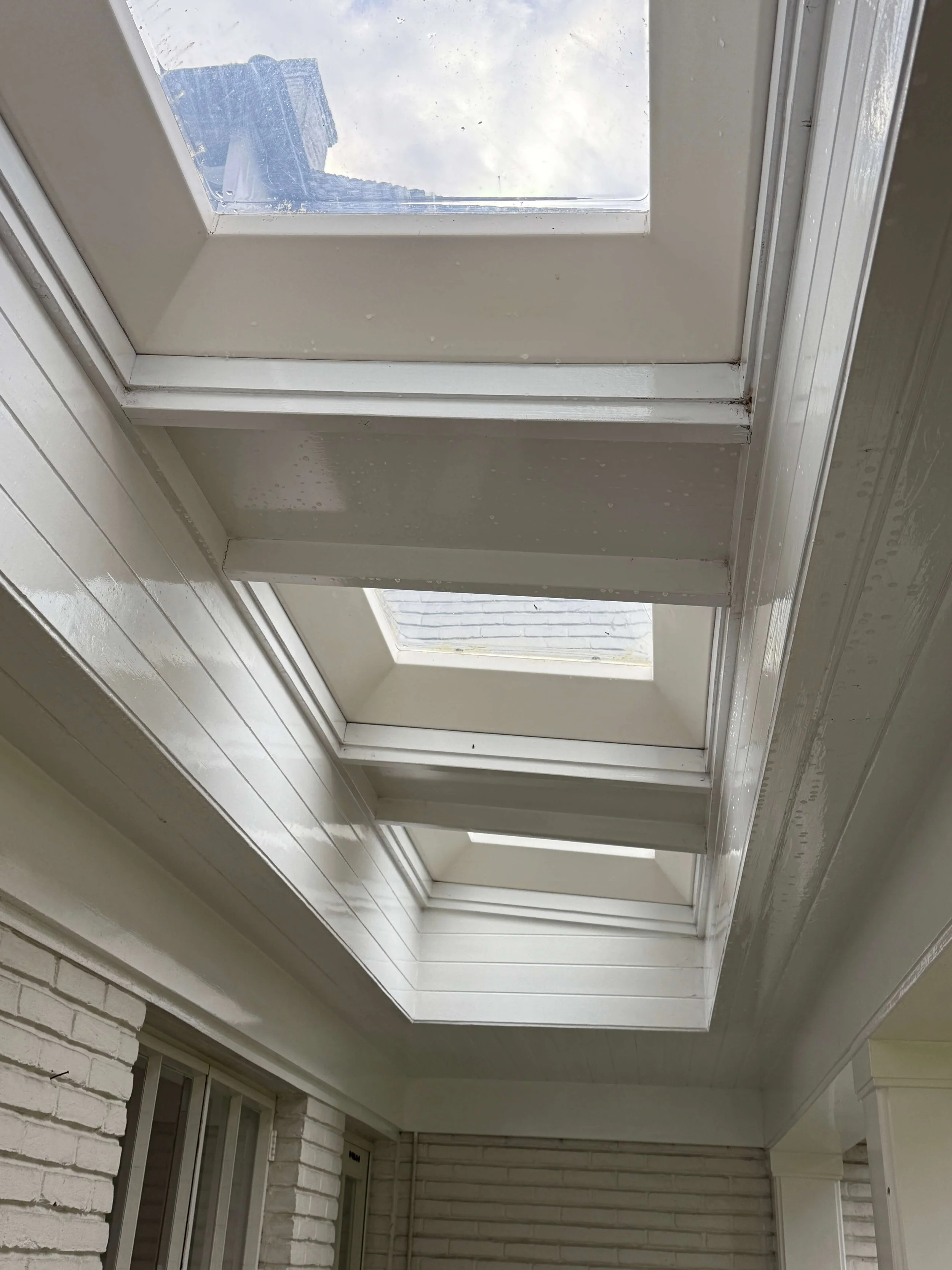 Witte dakconstructie met meerdere lichtkoepels en aansluitende buitenpanelen.