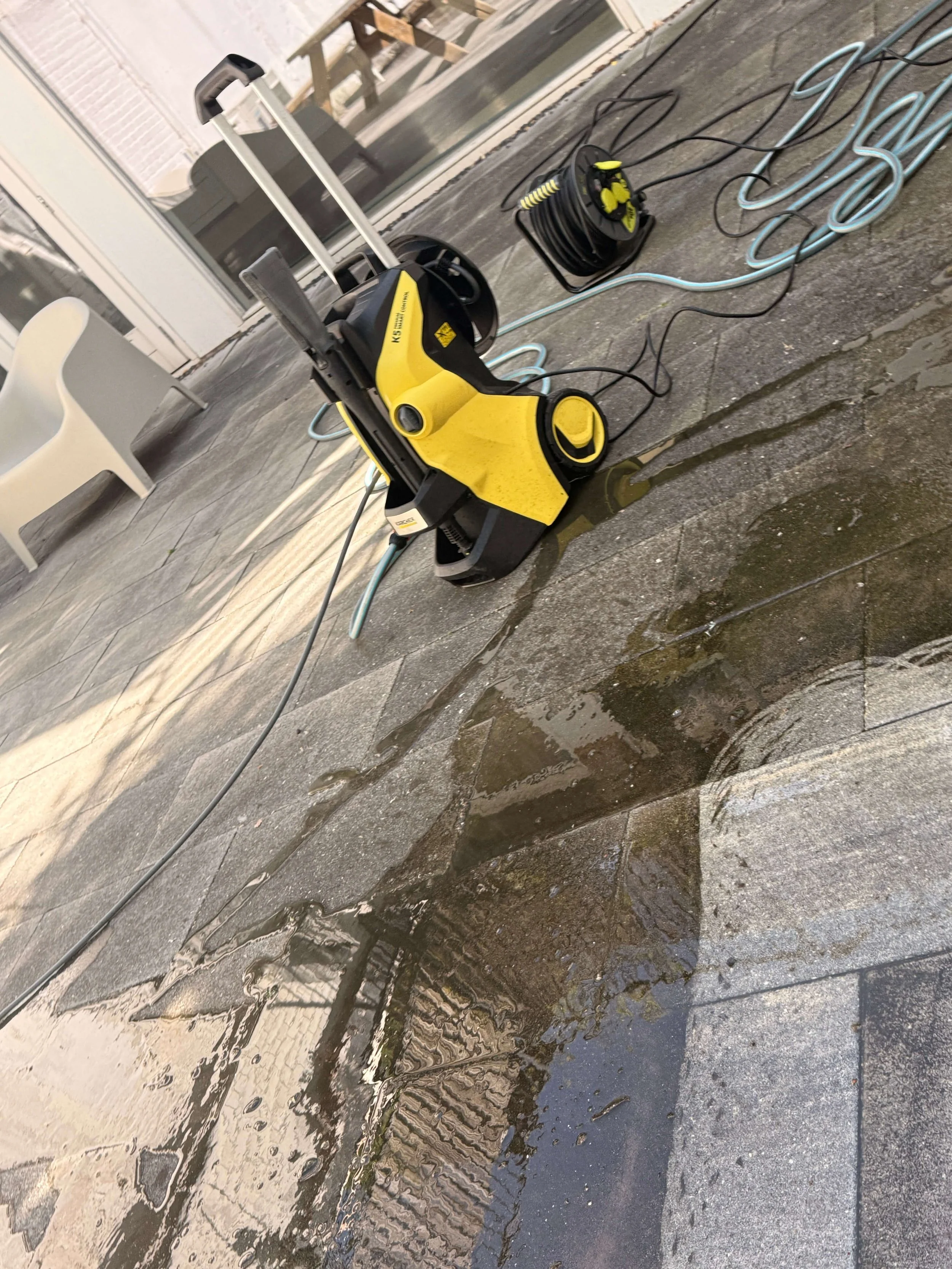 Professionele reinigingsapparatuur op een natte terrasvloer.