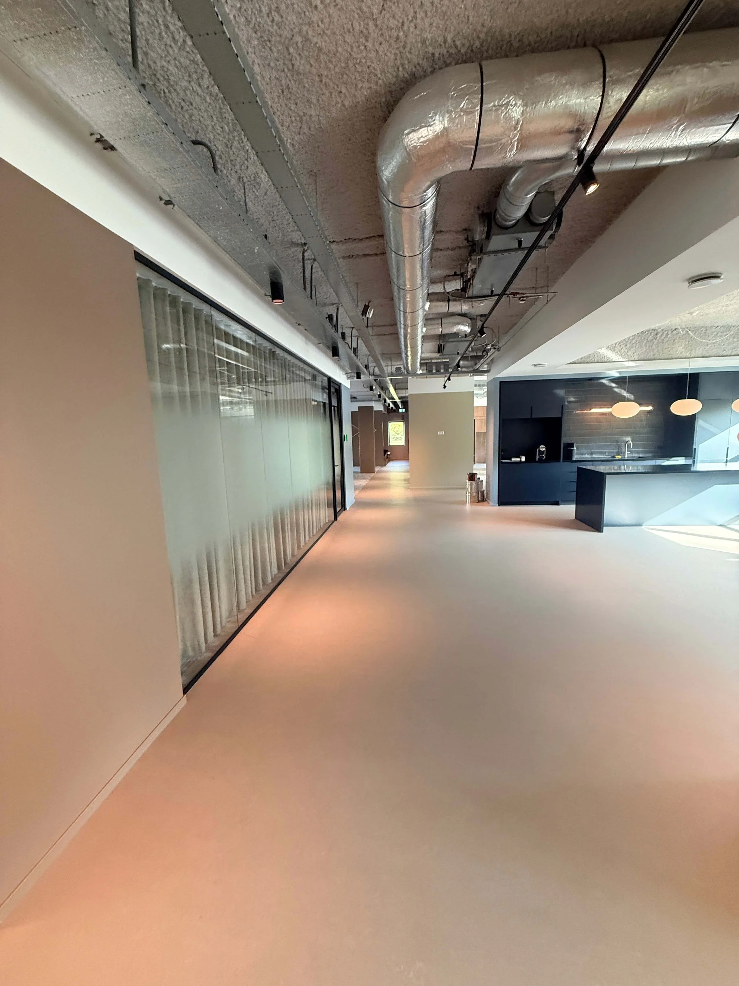 Opgeruimde commerciële ruimte met glazen wanden en open plafond na bouwwerkzaamheden.
