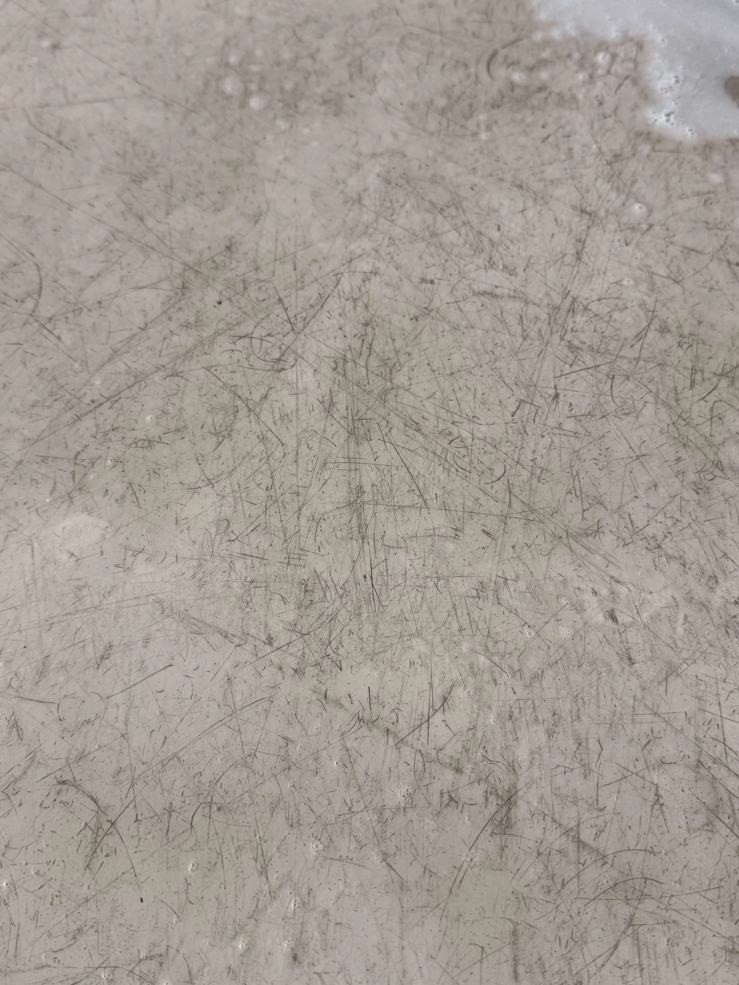 Close-up van een grijs oppervlak met veel zichtbare krassen en gebruikssporen.