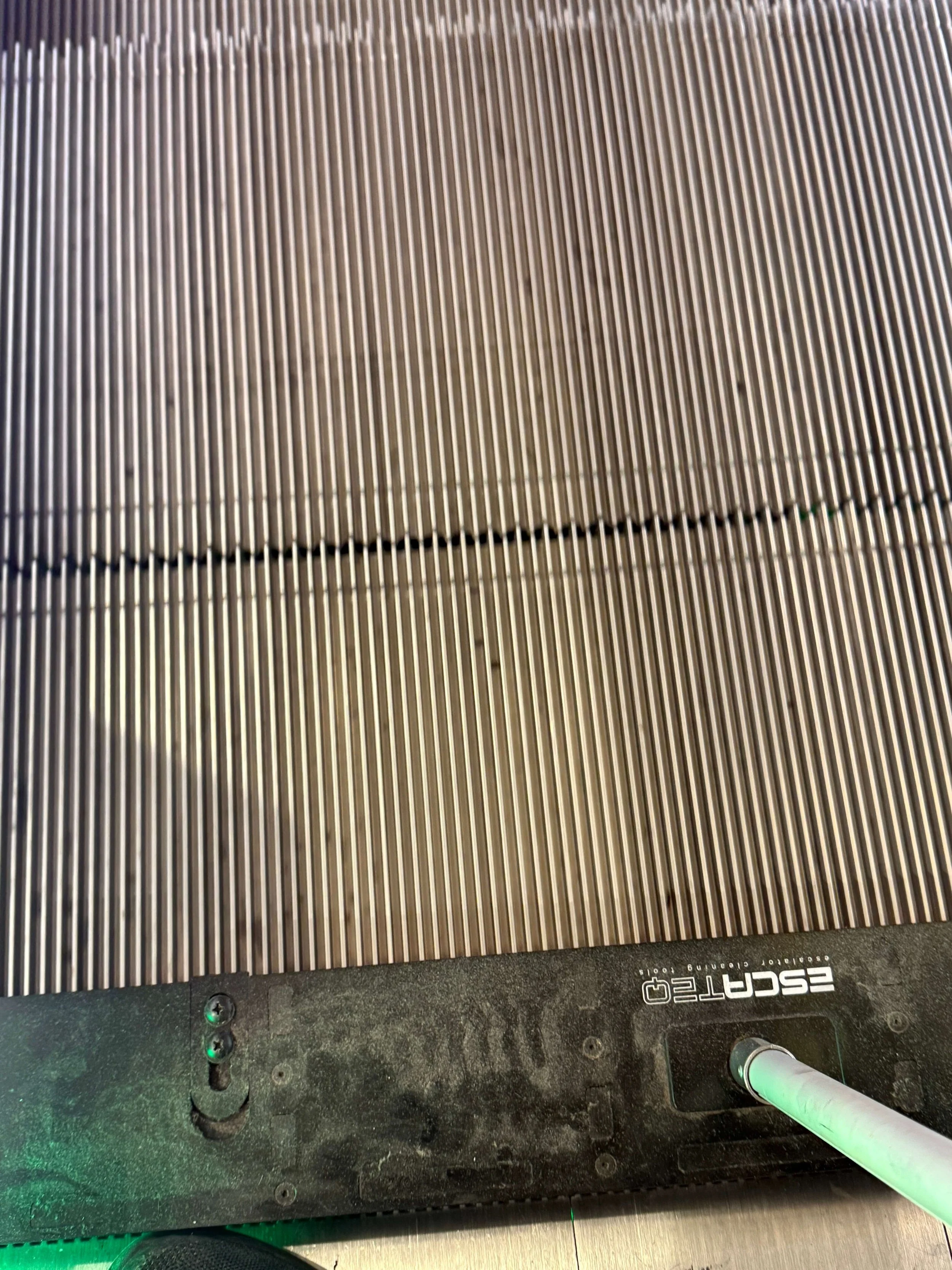 Close-up van de metalen treden van een roltrap tijdens specialistische reiniging.