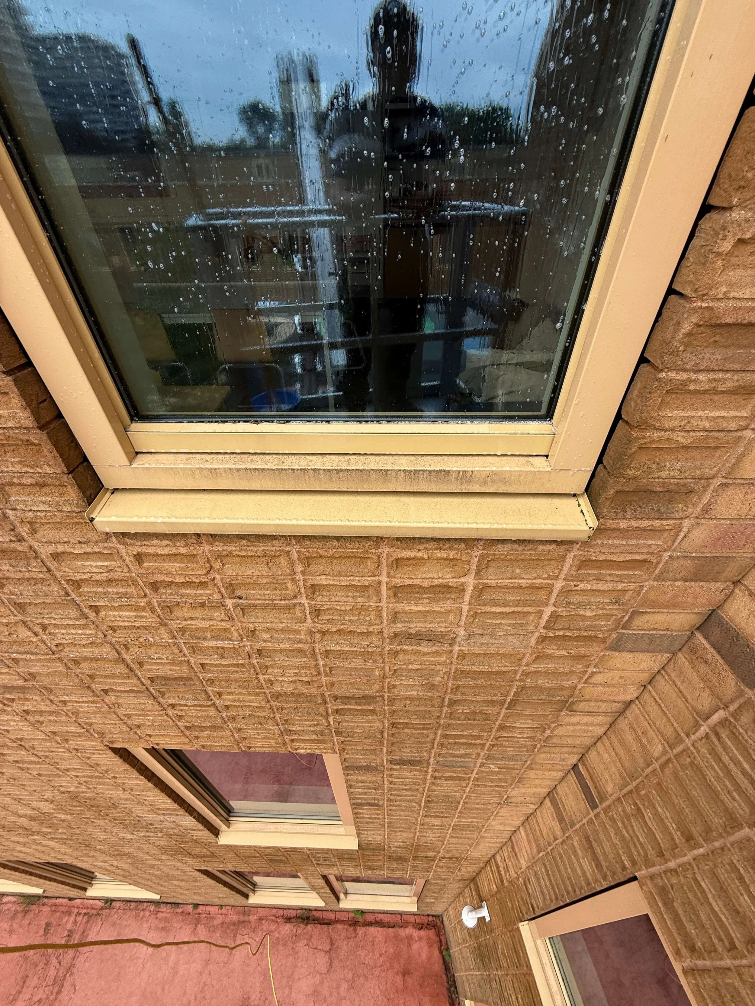 Raam met zichtbare waterdruppels aan de buitenzijde van een gebouw.