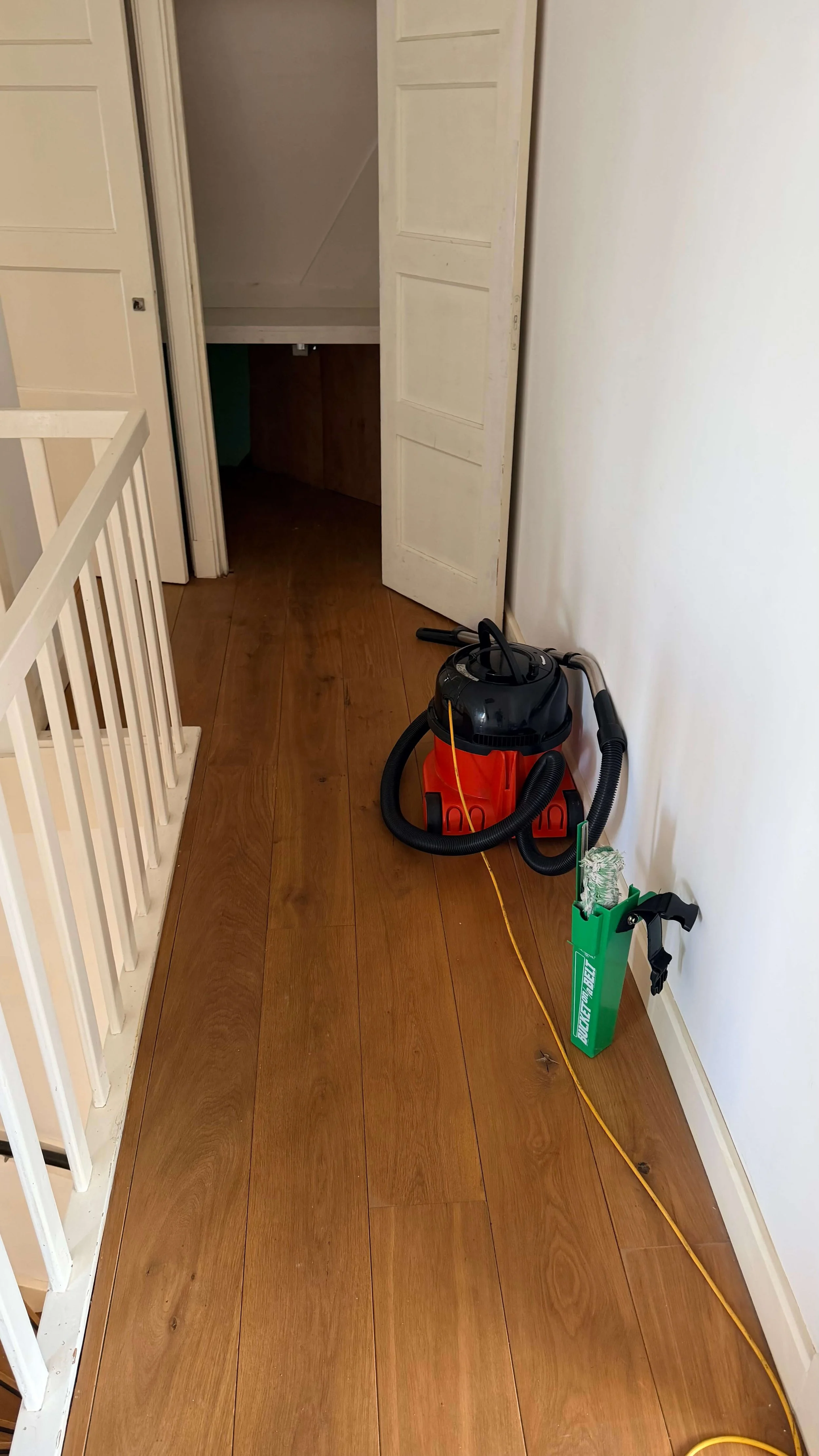 Vacuum cleaner and cleaning equipment in a home with wooden flooring.