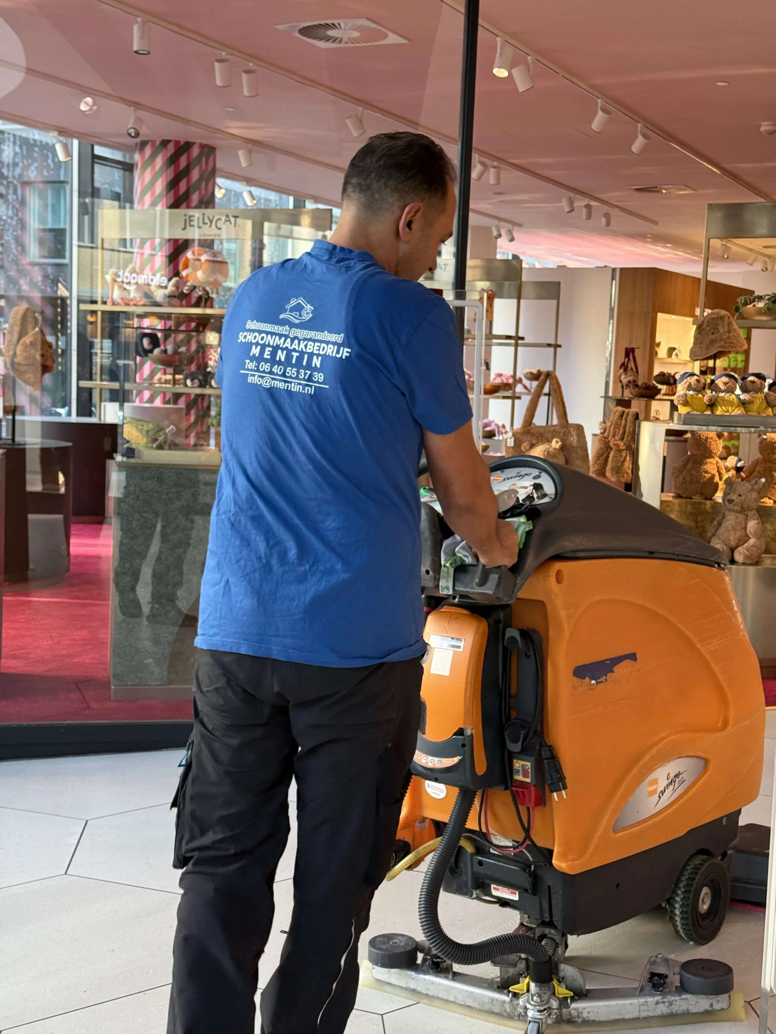 Schoonmaakmedewerker van Mentin reinigt een winkelvloer met een professionele schrobmachine.