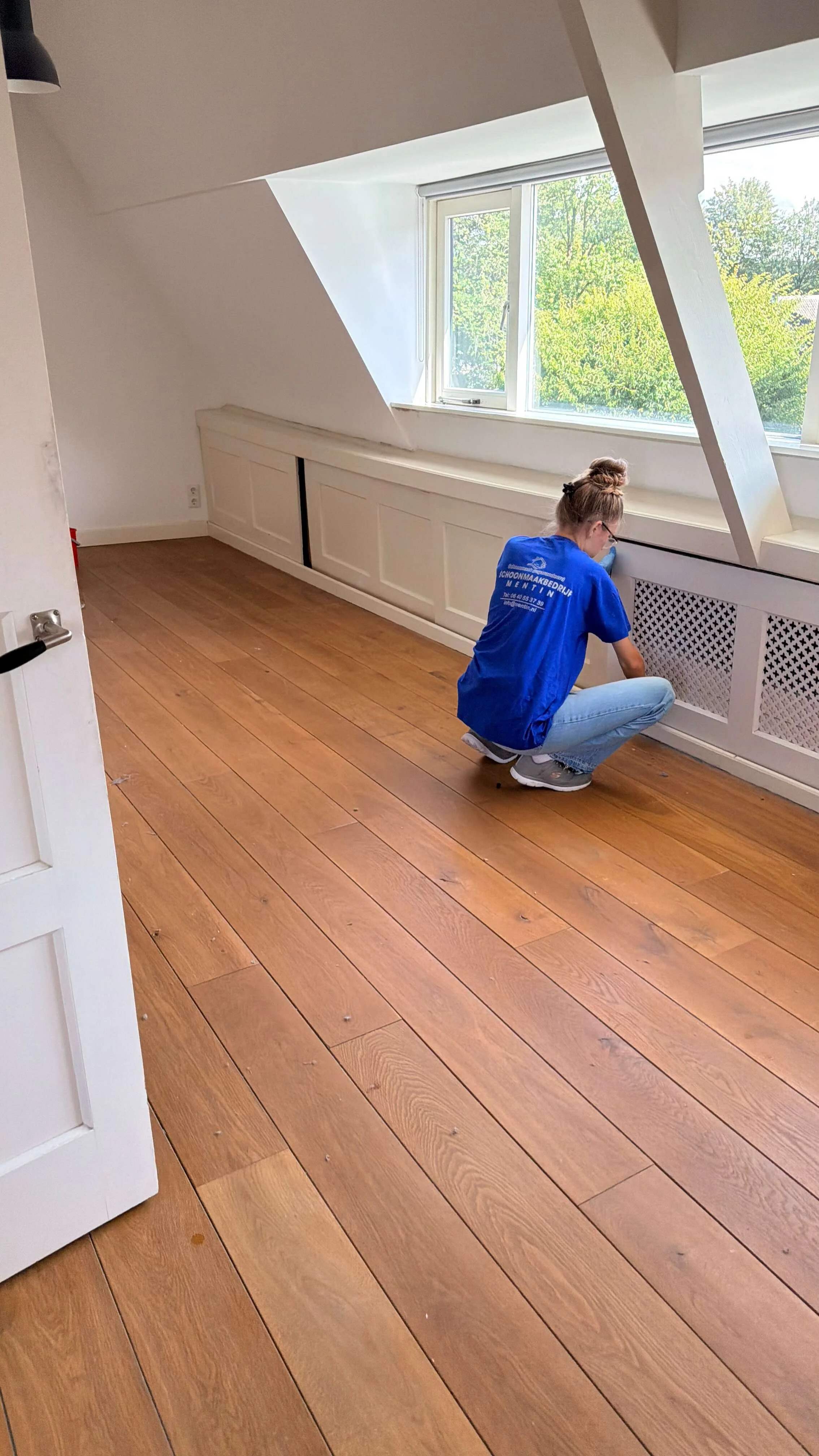 Schoonmaakmedewerker reinigt een ruimte in een woning na werkzaamheden.