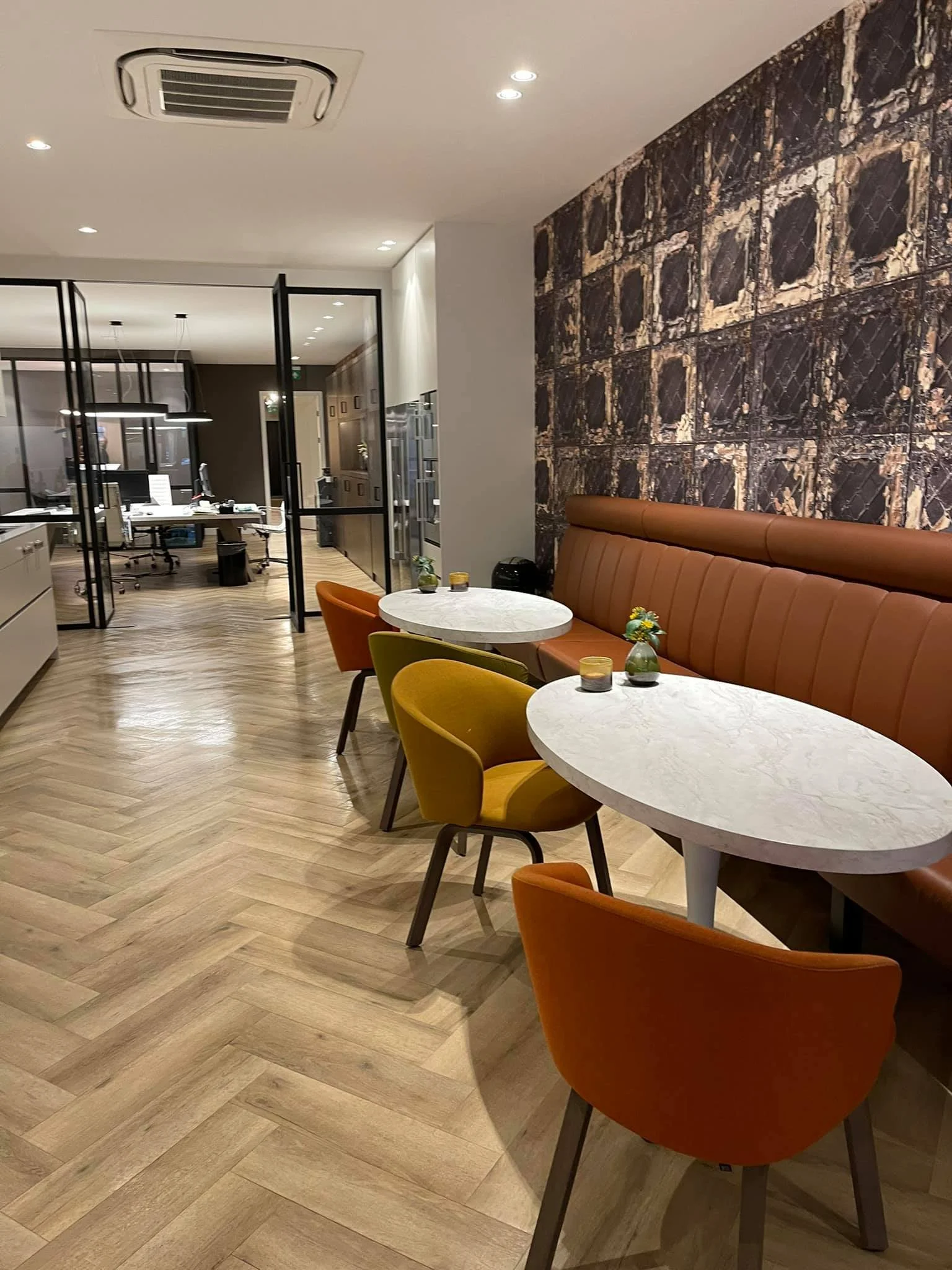 Kantoorinterieur met glazen scheidingswanden, vergadertafels en zitplaatsen.