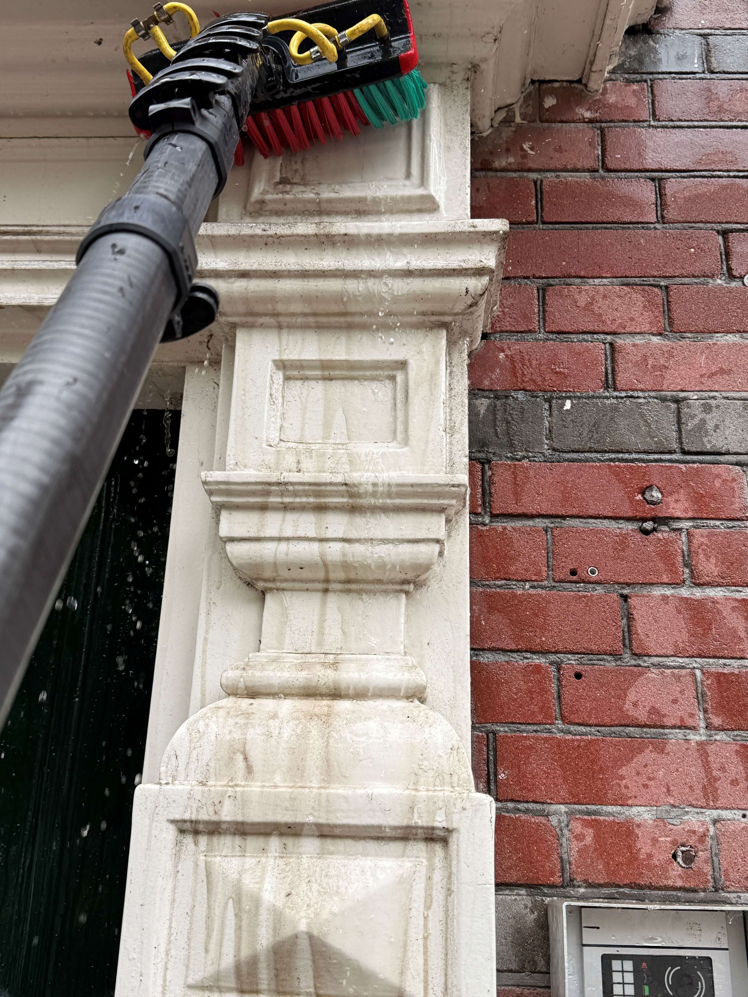 Reinigingsborstel op een gemetselde gevel tijdens gevelreiniging.