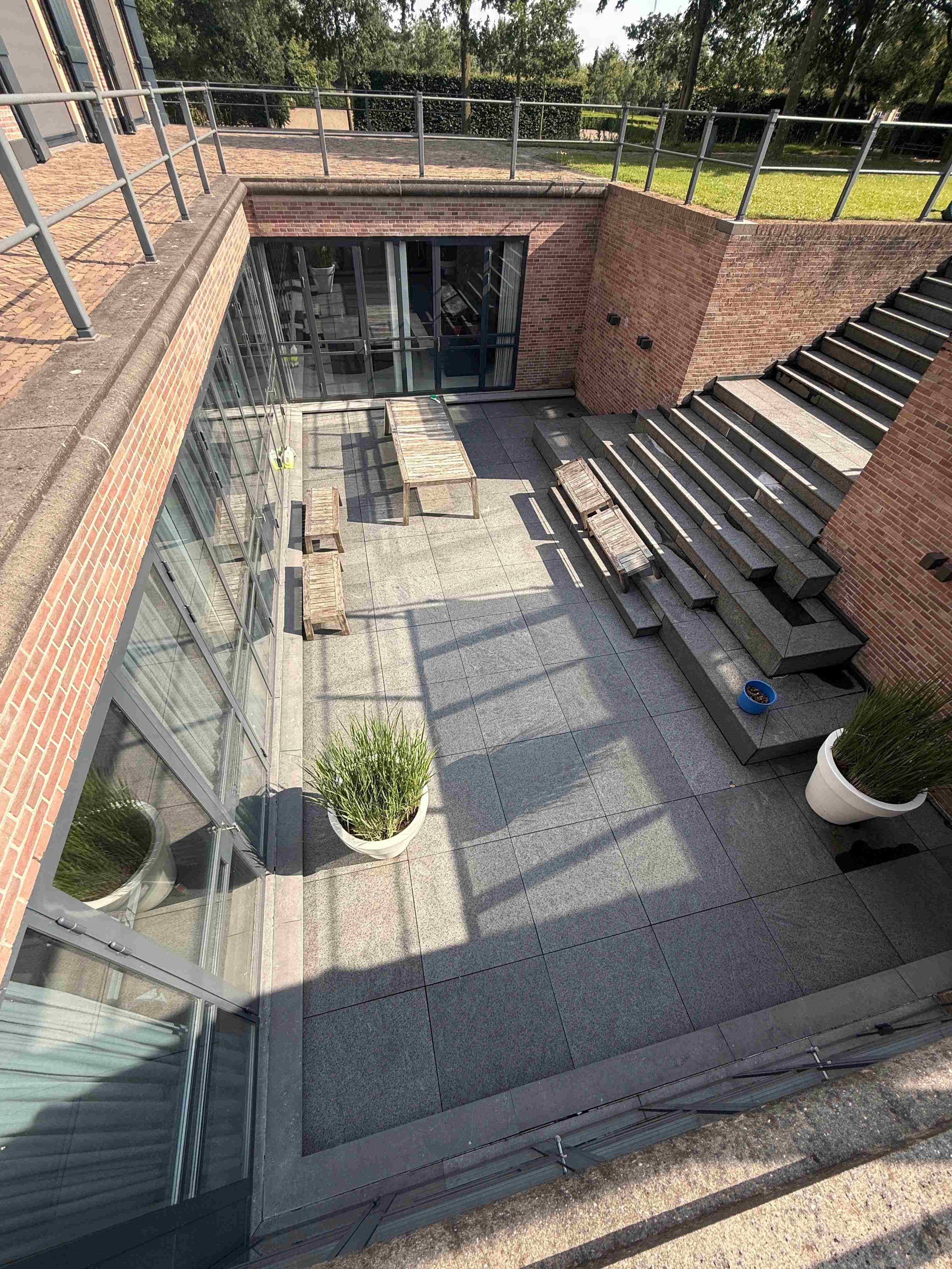 Bestraat terras met trappen en zitgedeelte.