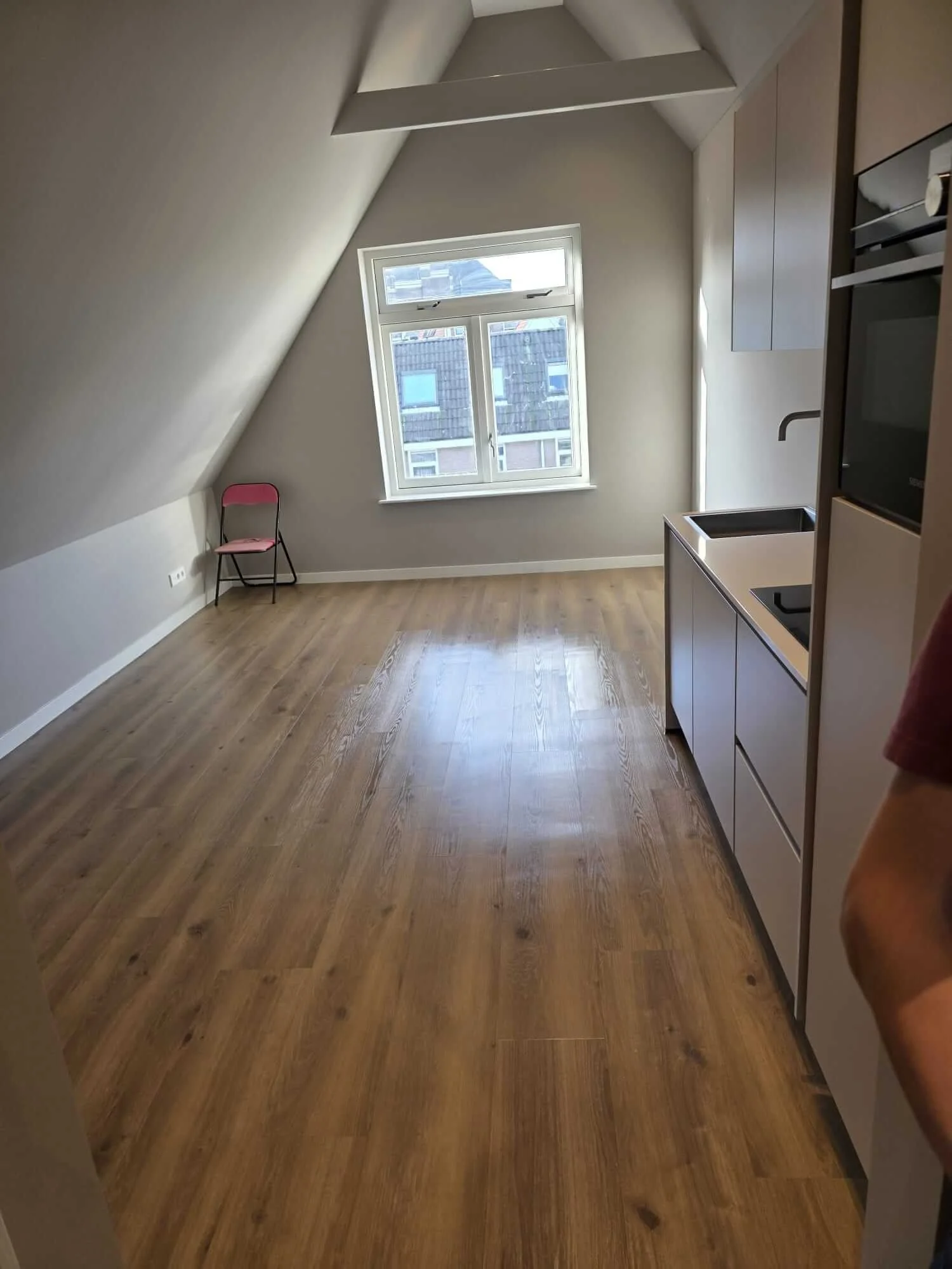 Lege gerenoveerde ruimte met keuken en houten vloer na schoonmaak.
