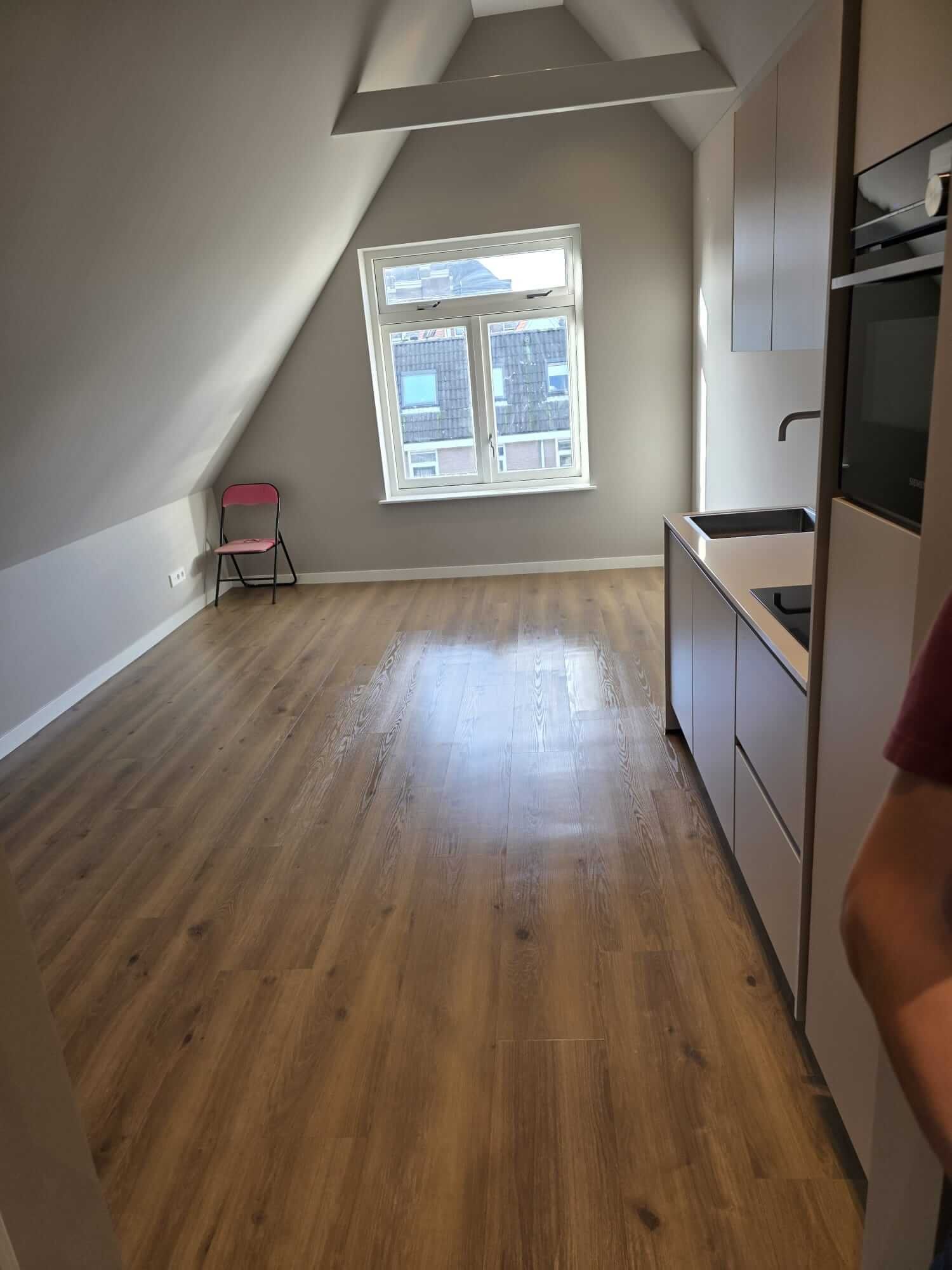 Schone keuken met witte kasten, werkblad en tegelvloer na afwerking.