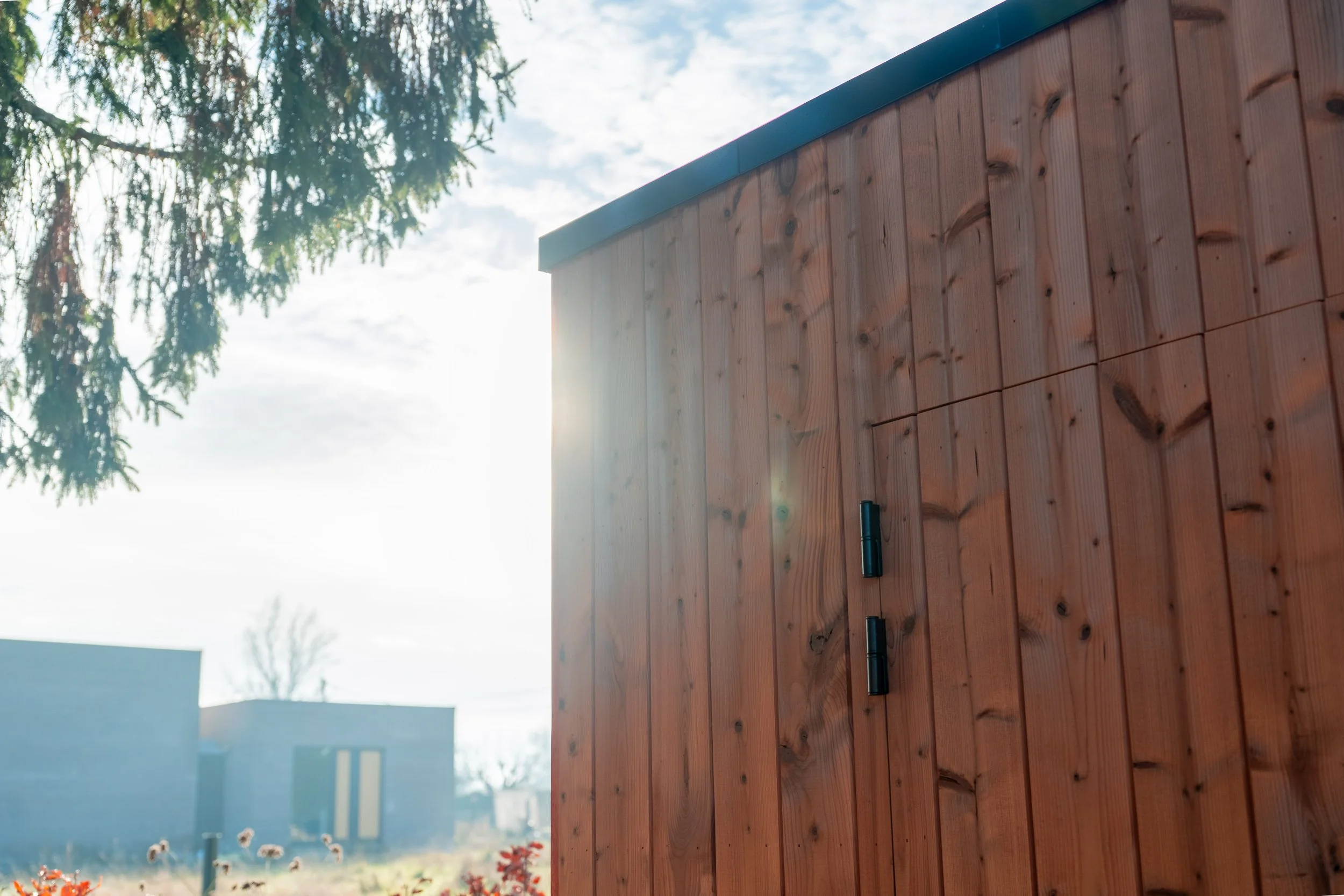 Houten gevel van een huis met een open raam, gezien vanuit een schuine hoek.