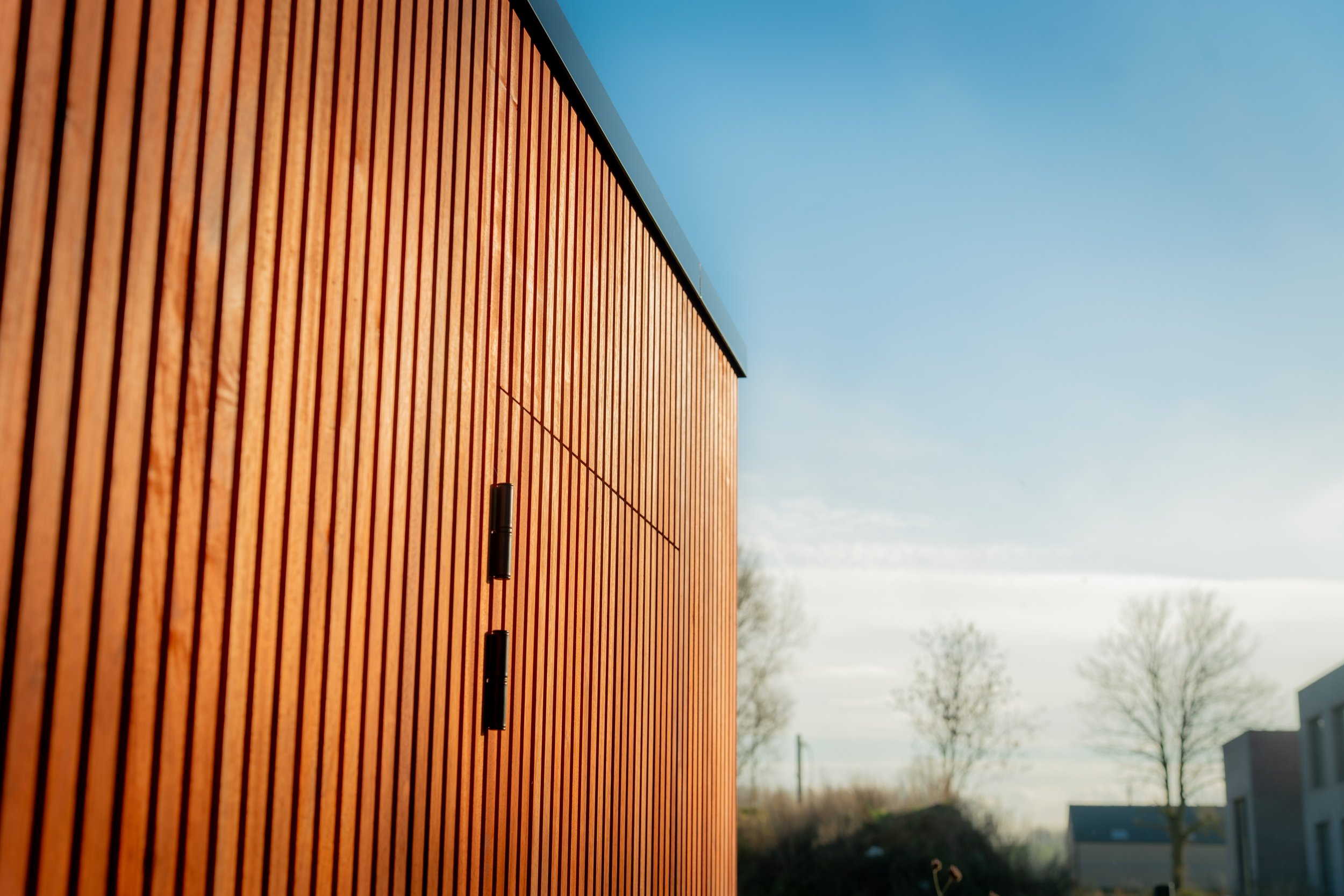 Een modern gebouw met verticale houten gevelbekleding onder een blauwe hemel.